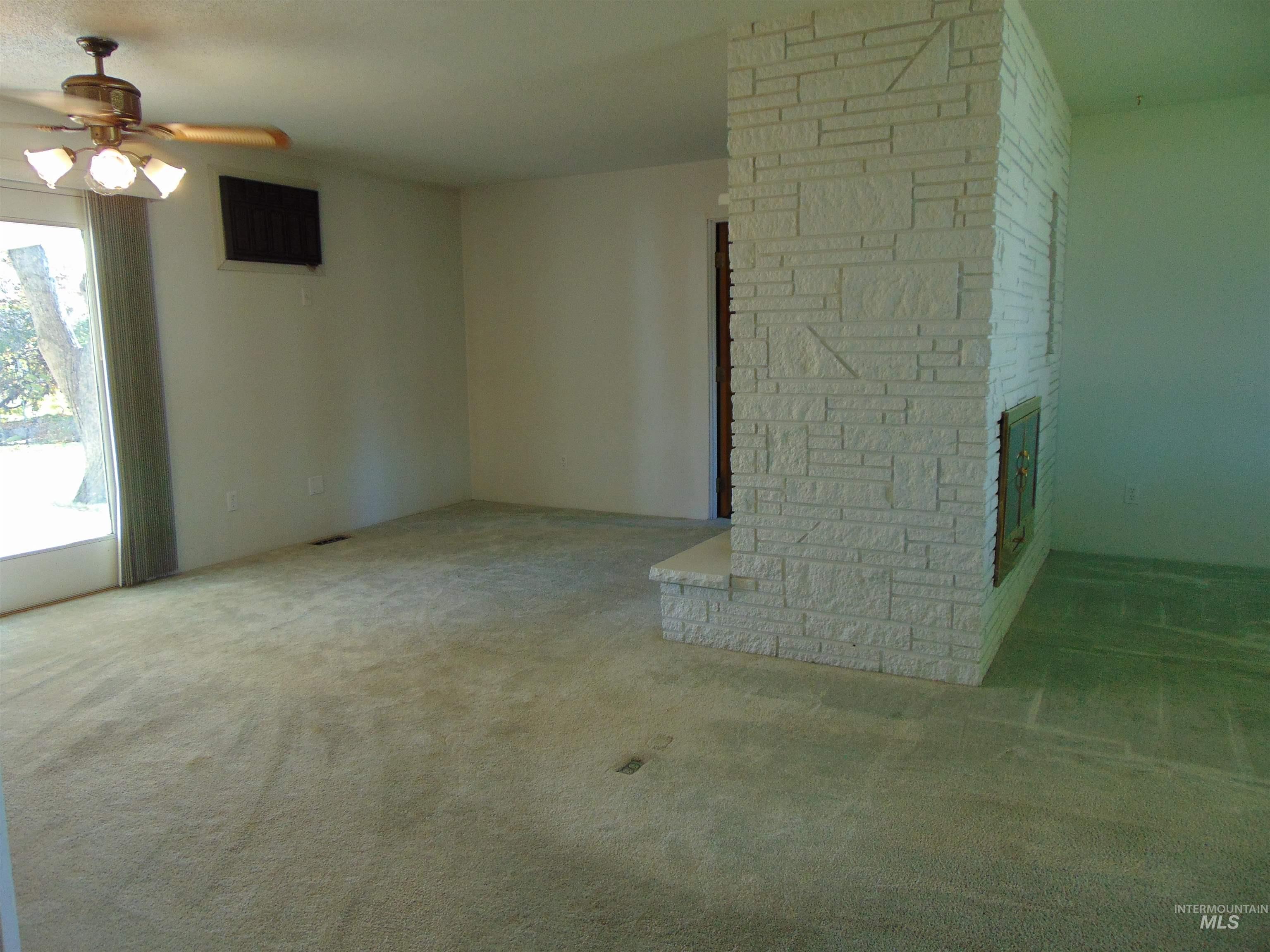 Spare room featuring carpet floors, a fireplace, and a ceiling fan