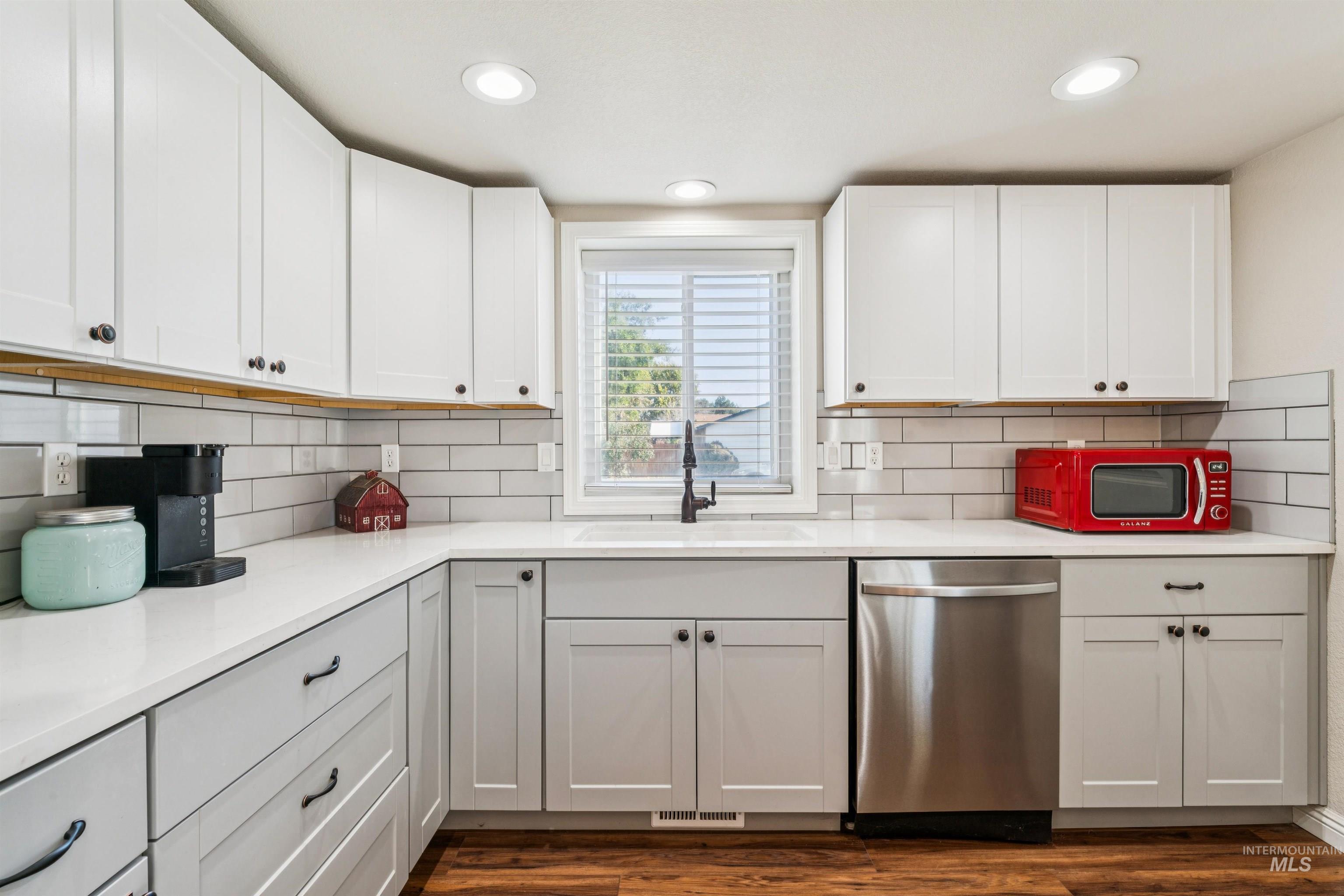 Kitchen featuring dishwasher, white cabinetry, recessed lighting, dark wood finished floors, and backsplash
