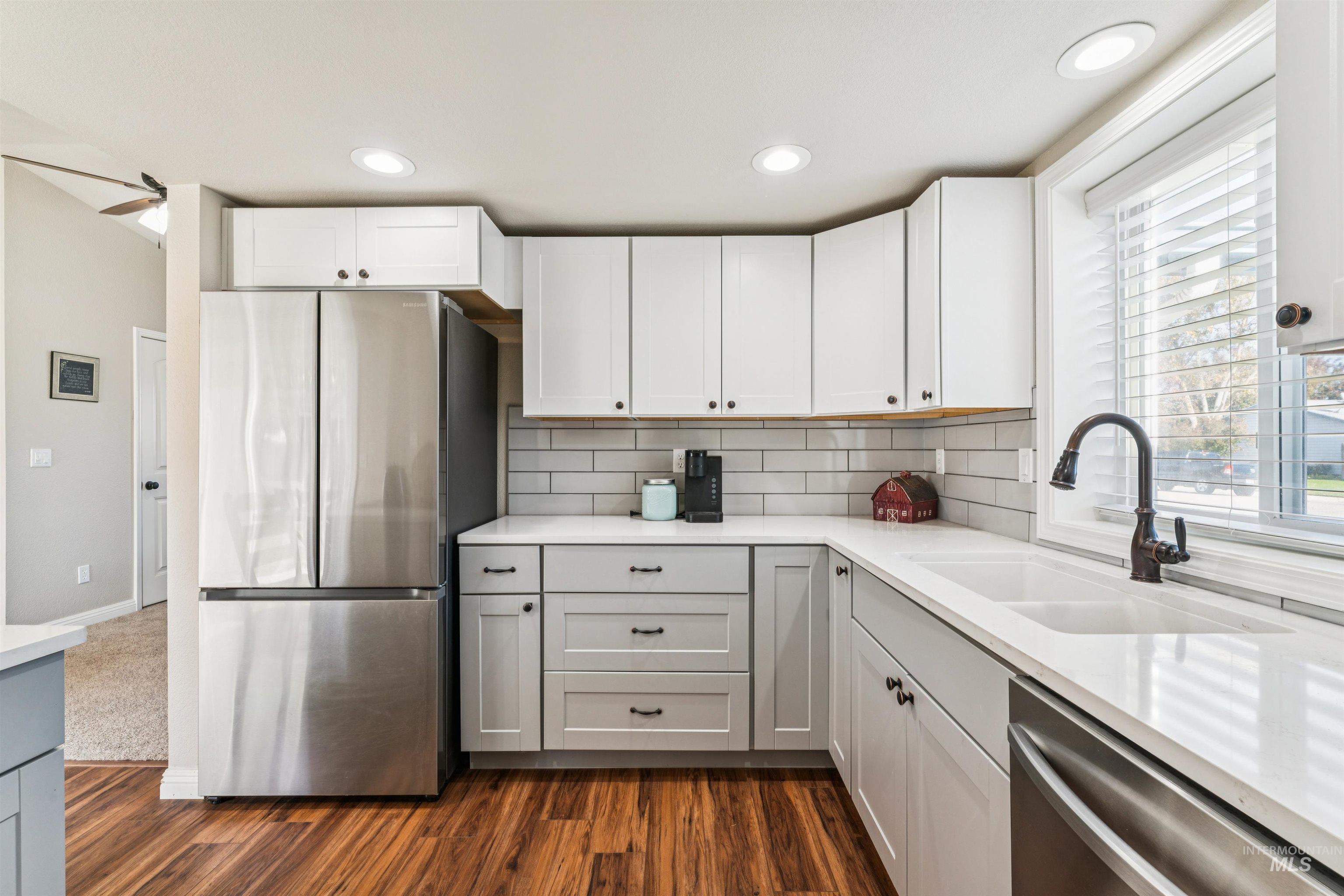 Kitchen with stainless steel appliances, white cabinetry, gray cabinetry, tasteful backsplash, and dark wood finished floors