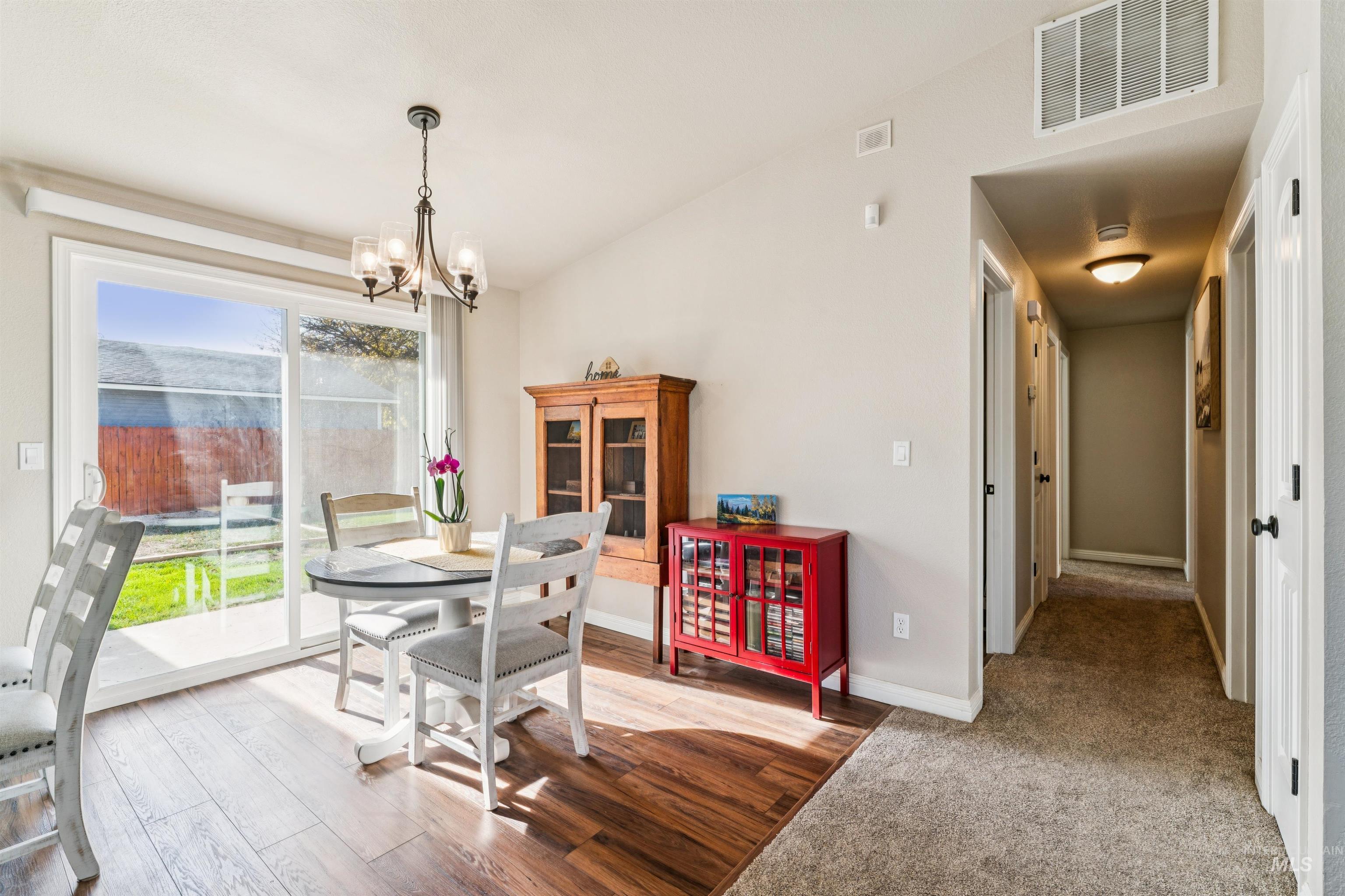 Dining room featuring light wood-type flooring, a chandelier, and vaulted ceiling