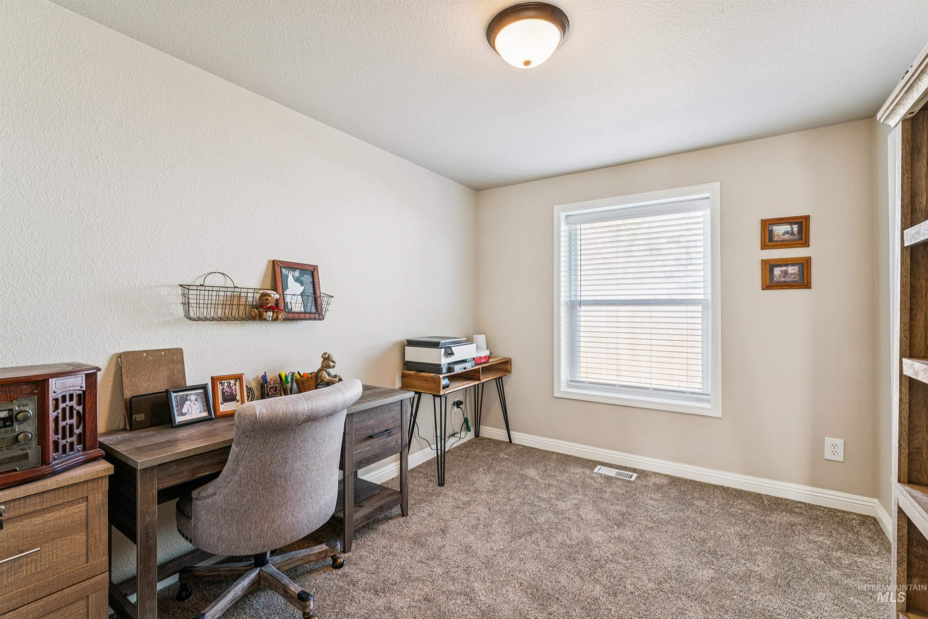 Carpeted home office featuring baseboards