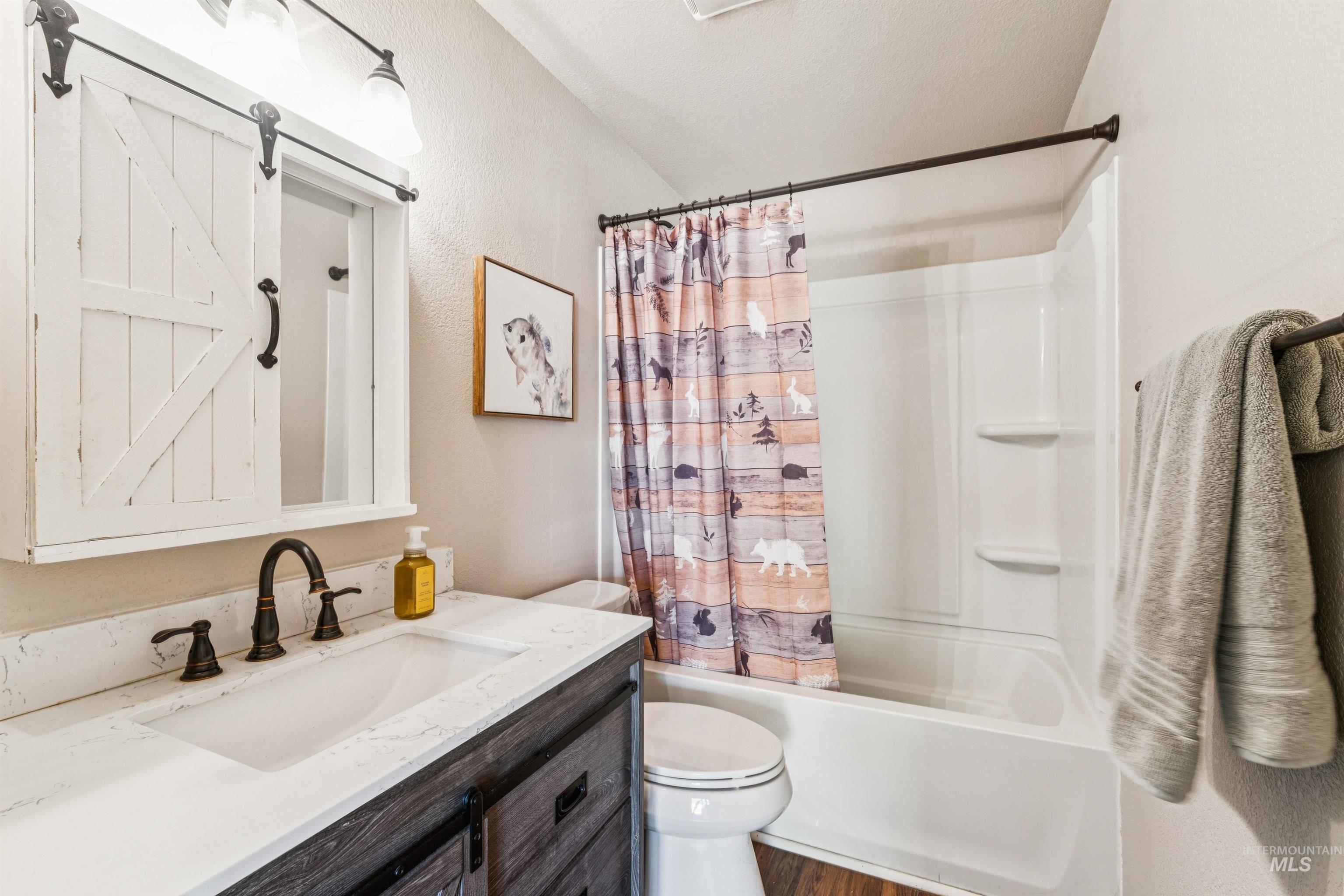 Full bath with vanity, shower / tub combo, and dark wood-type flooring