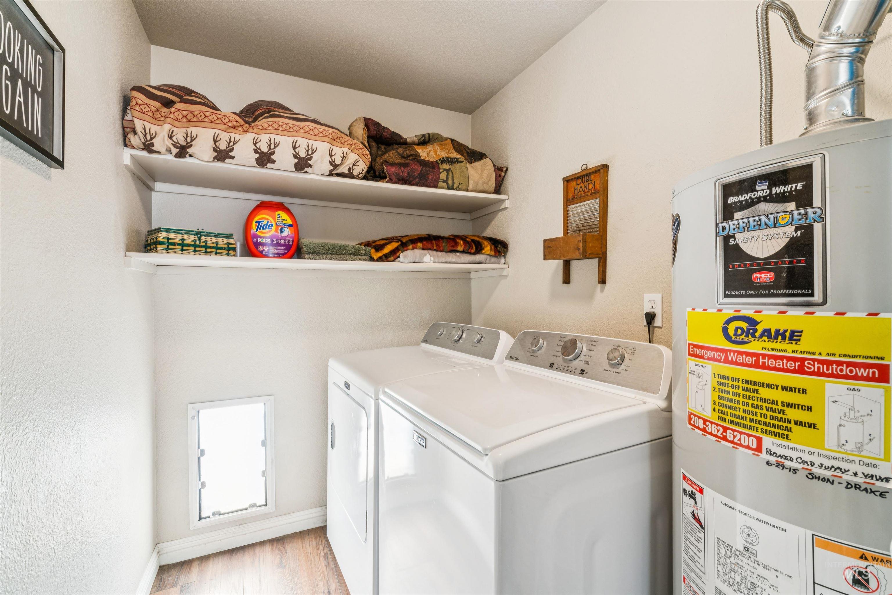Laundry room featuring water heater, light wood-type flooring, and washer and clothes dryer
