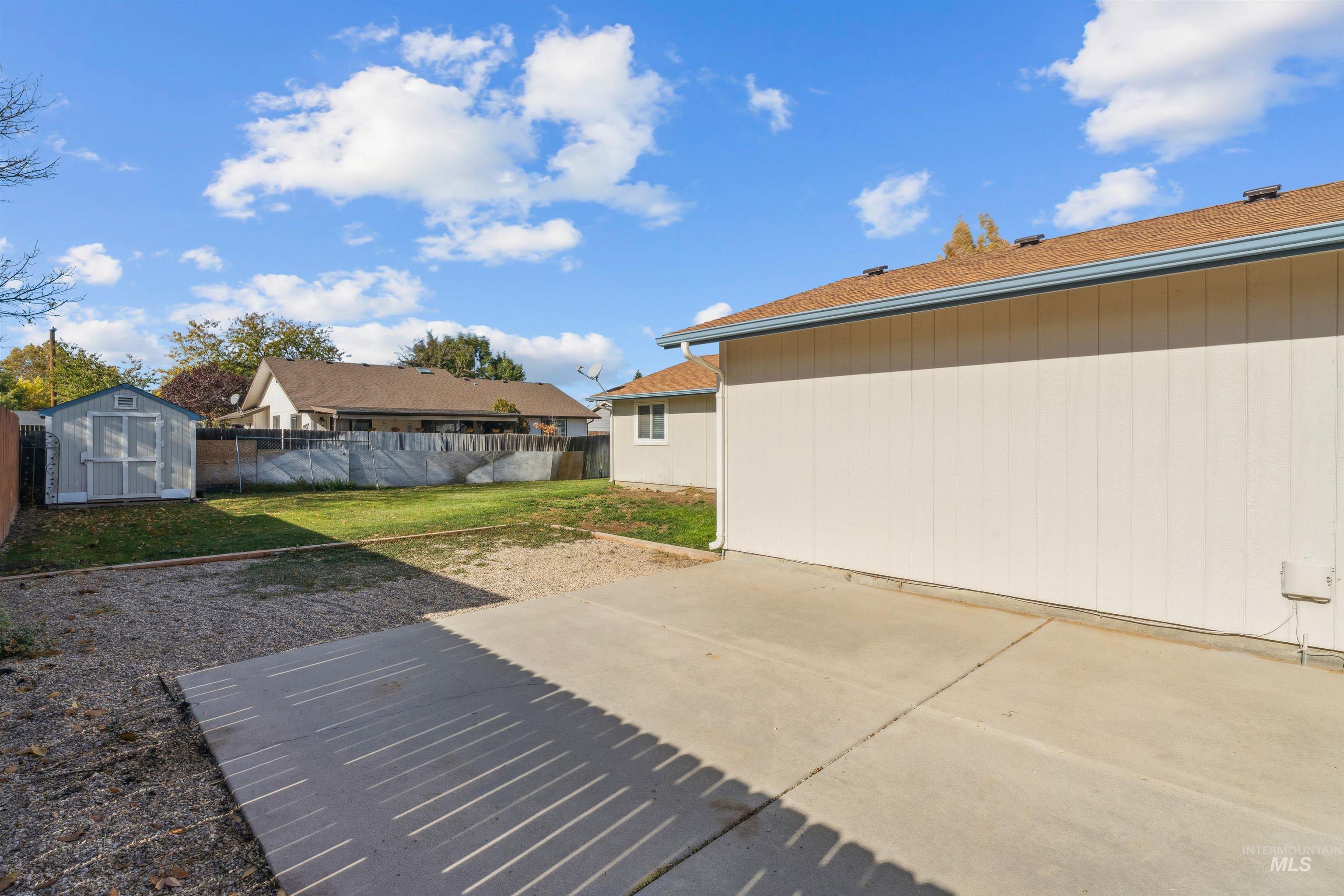 Fenced backyard featuring a storage shed and a patio