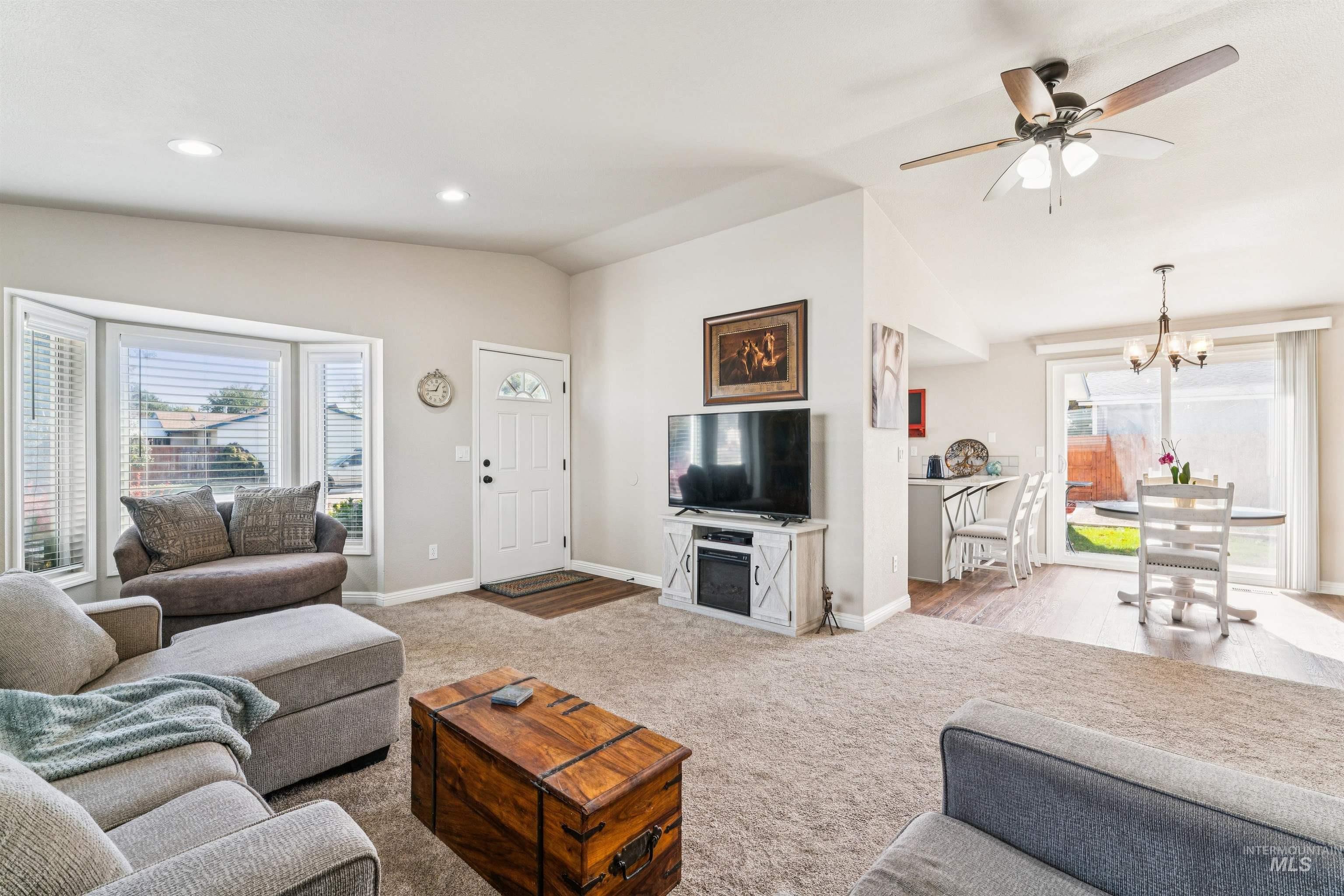 Carpeted living area featuring ceiling fan, lofted ceiling, recessed lighting, and a chandelier