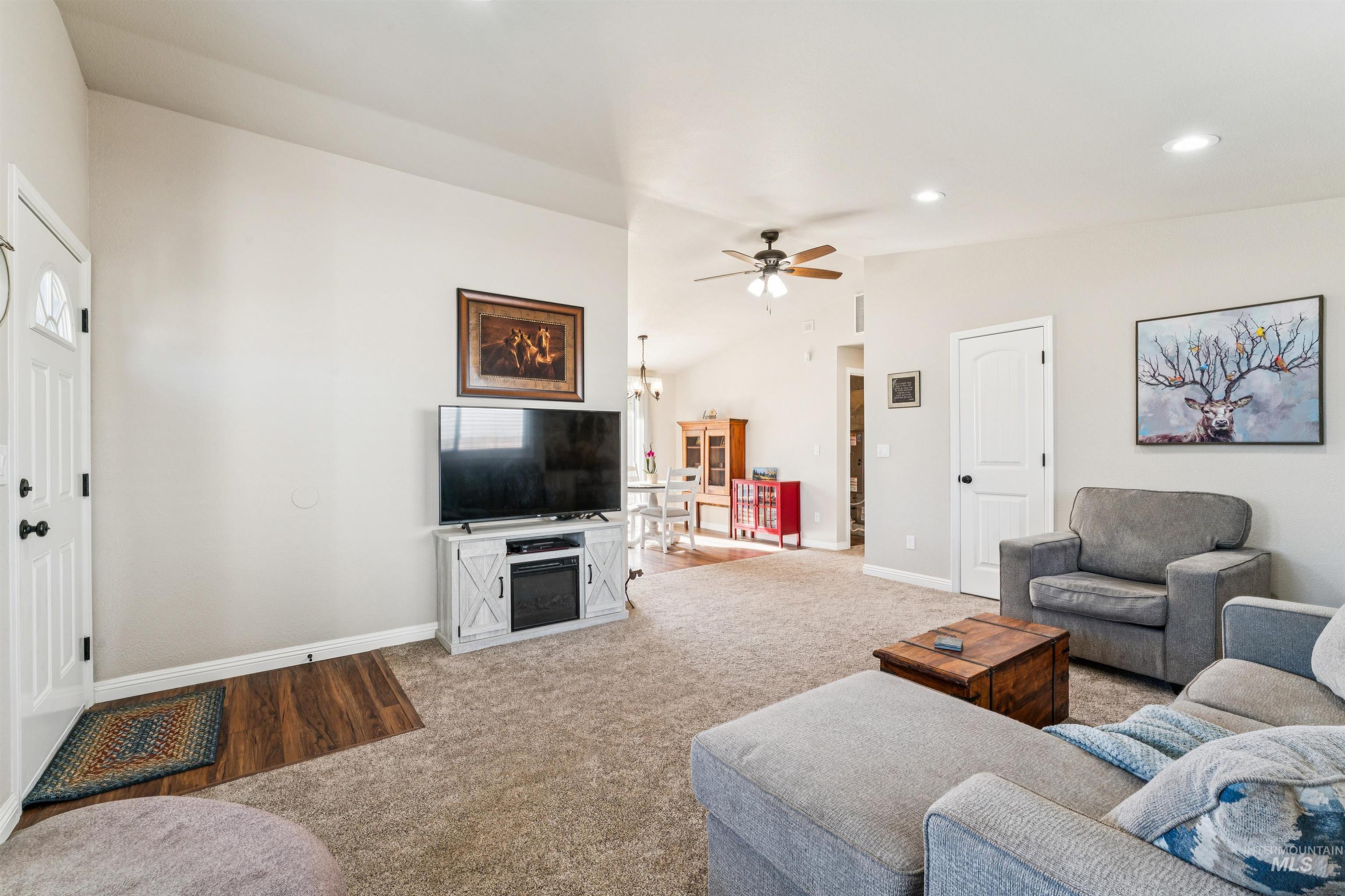 Living room with vaulted ceiling, carpet, ceiling fan, recessed lighting, and a chandelier