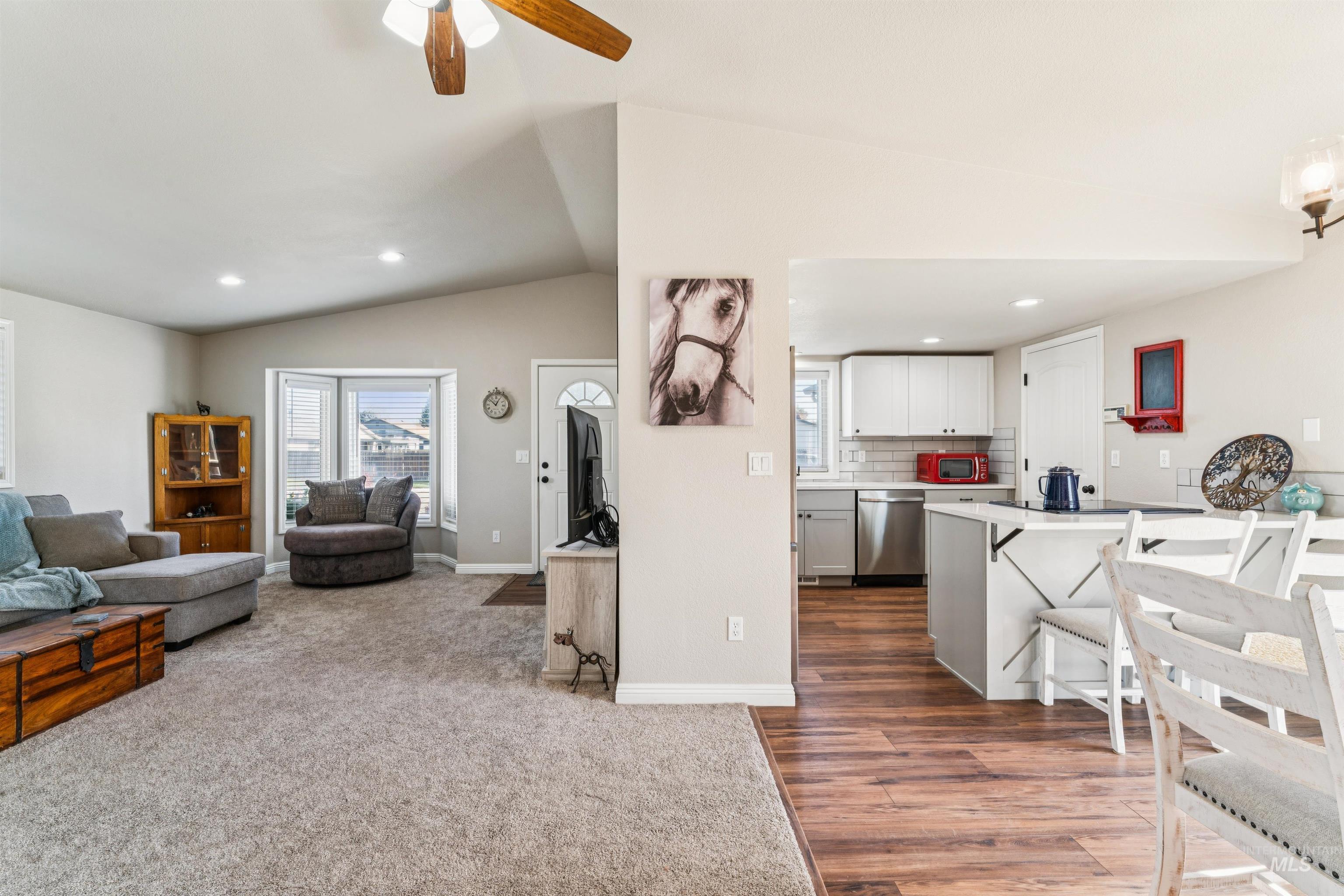 Living area with a ceiling fan, vaulted ceiling, healthy amount of natural light, recessed lighting, and dark carpet