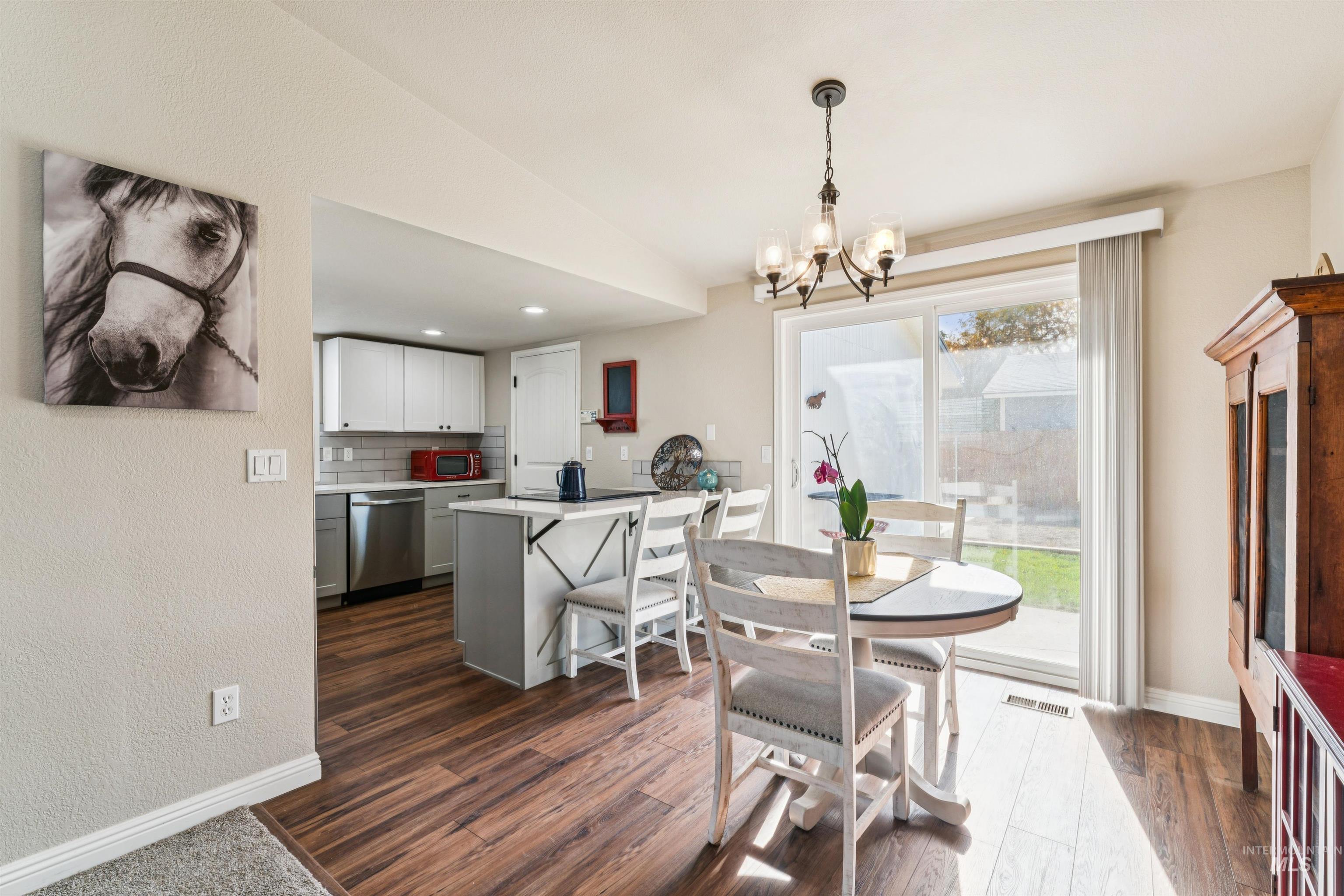 Dining space featuring dark wood-style flooring, a chandelier, a textured wall, and recessed lighting