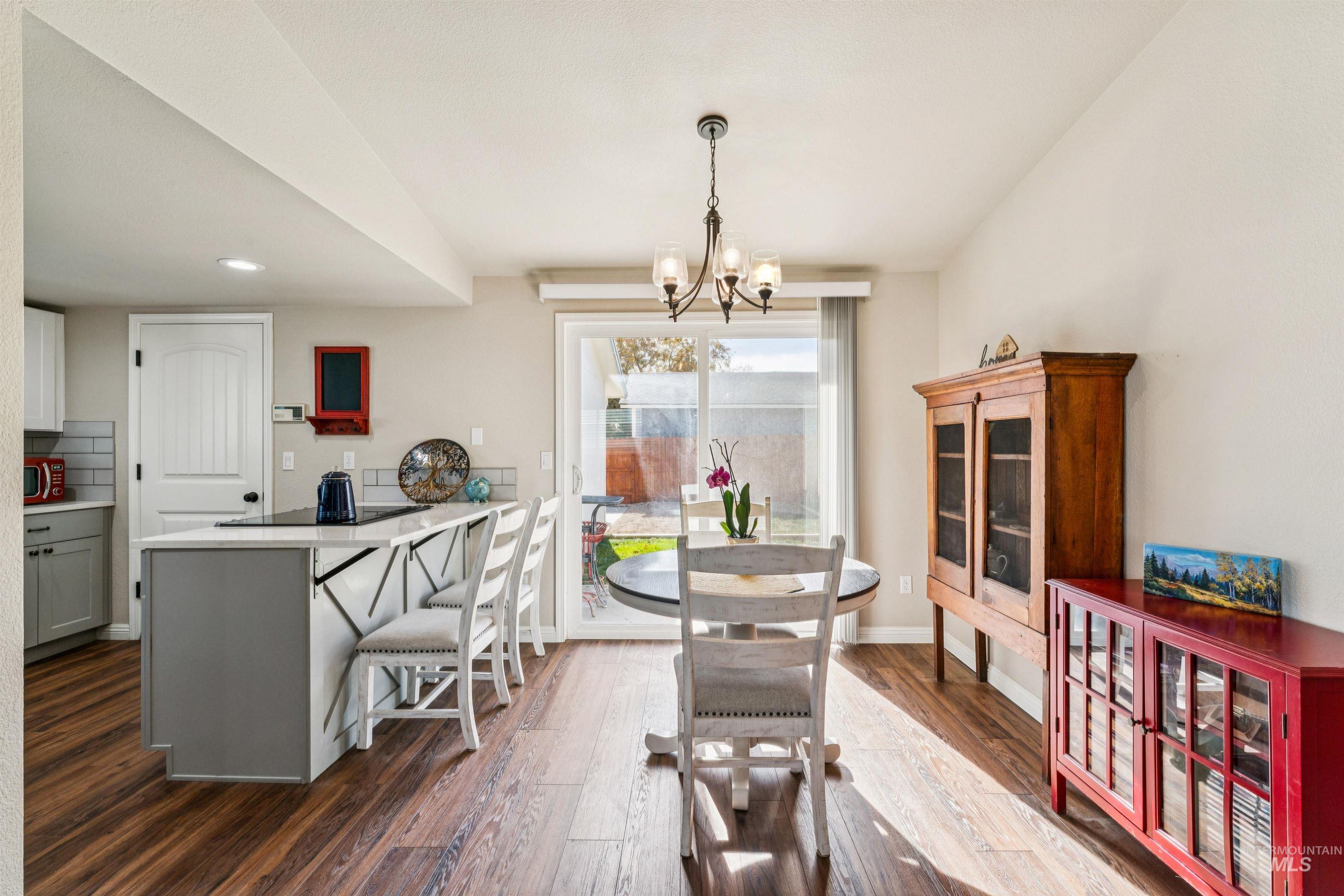 Dining space with dark wood-type flooring, a chandelier, and recessed lighting