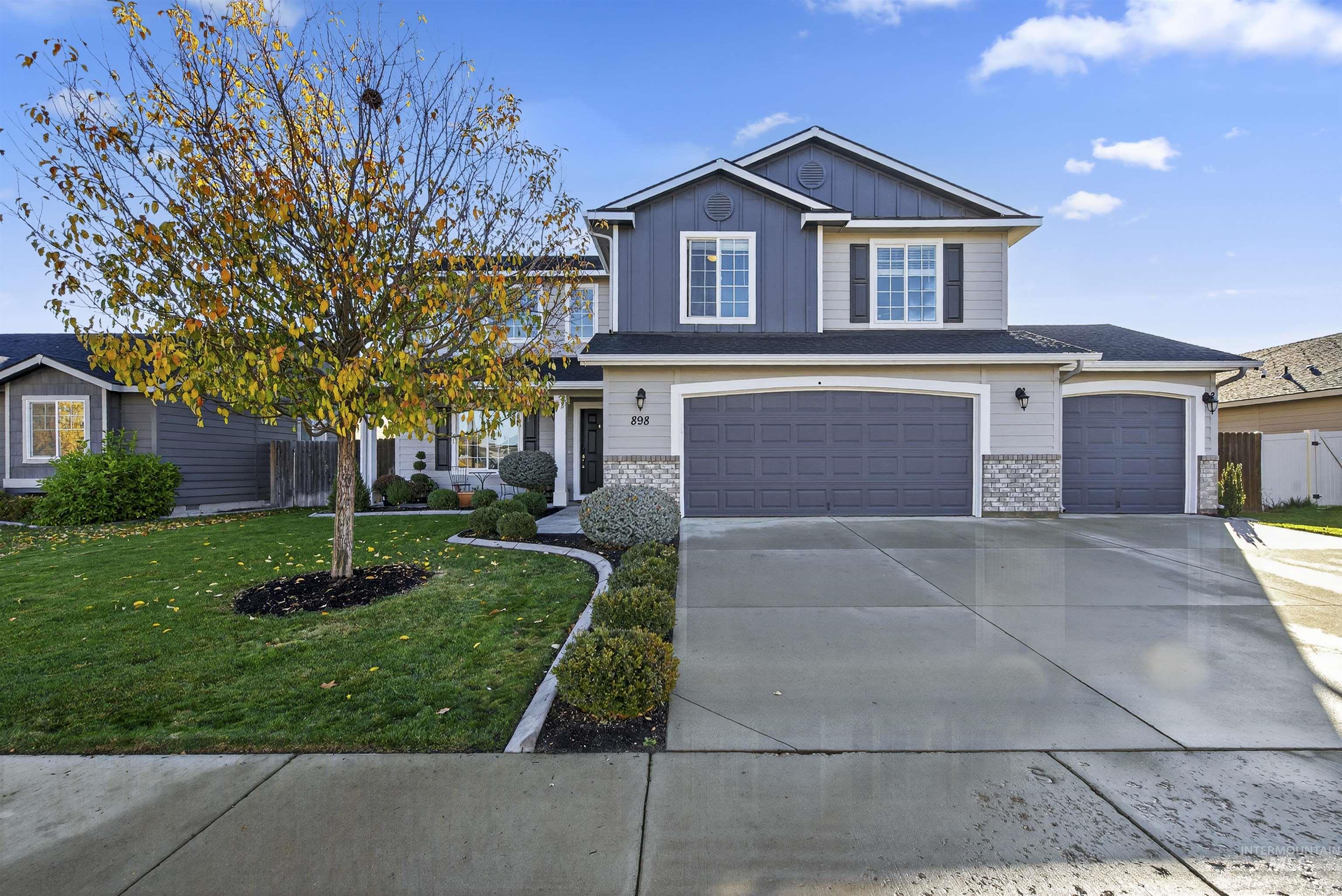 View of front of house with board and batten siding, concrete driveway, an attached garage, and stone siding