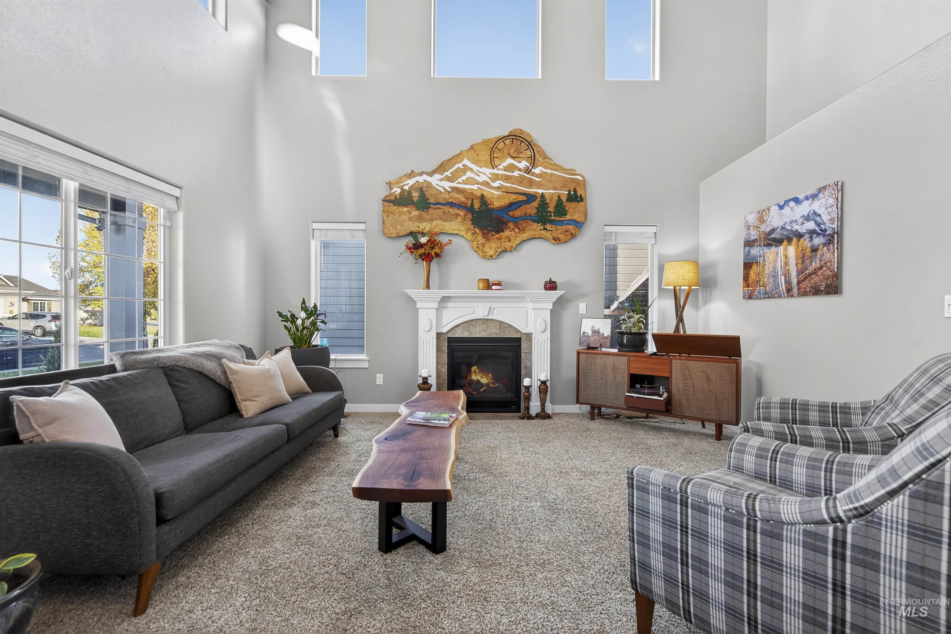 Living area featuring carpet, a fireplace with flush hearth, and a towering ceiling