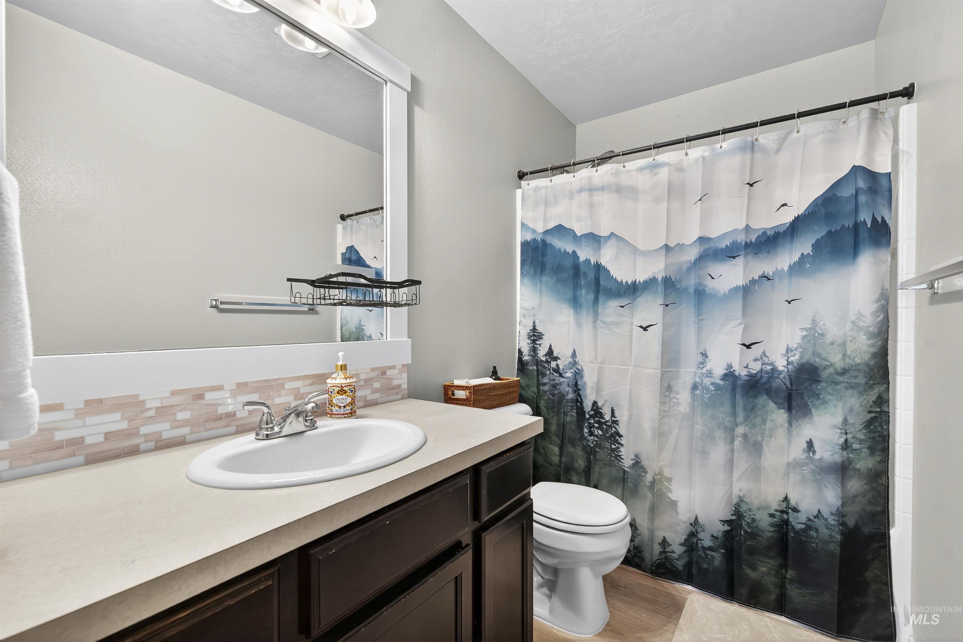 Bathroom featuring vanity, decorative backsplash, a shower with curtain, and light wood finished floors