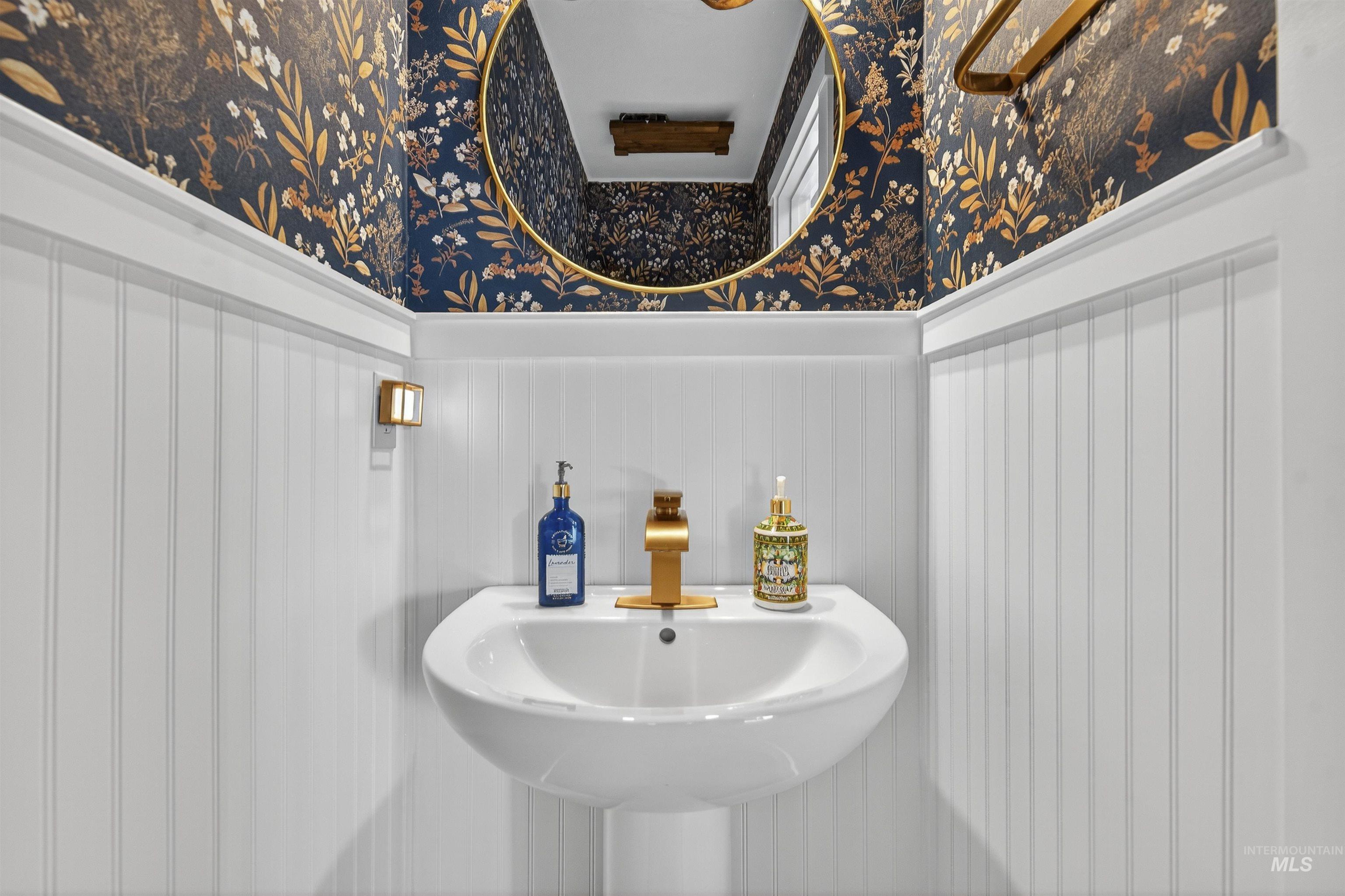 Bathroom with wainscoting and wallpapered walls