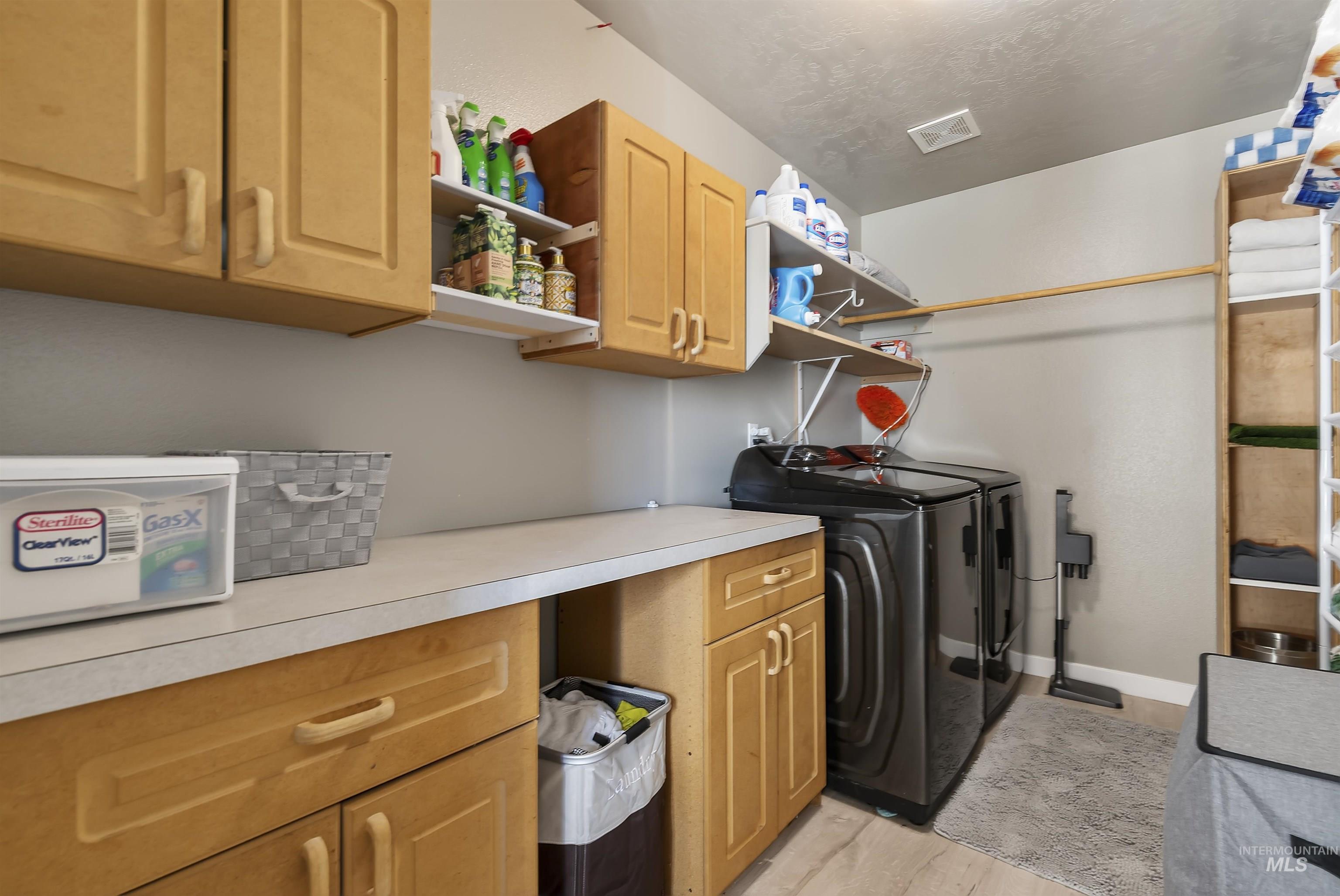 Washroom with cabinet space, independent washer and dryer, and light wood finished floors
