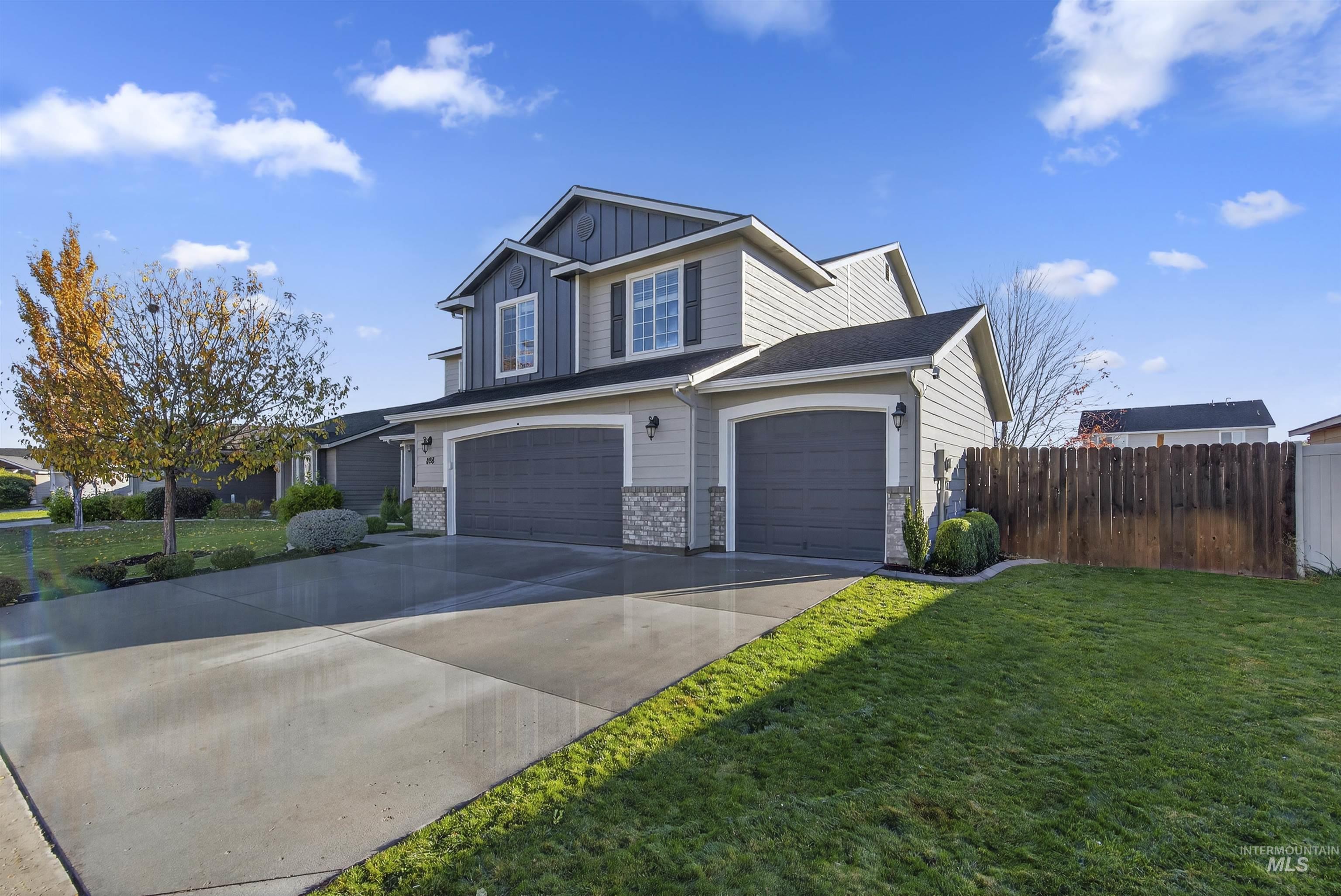 View of front of home featuring an attached garage, concrete driveway, board and batten siding, and stone siding