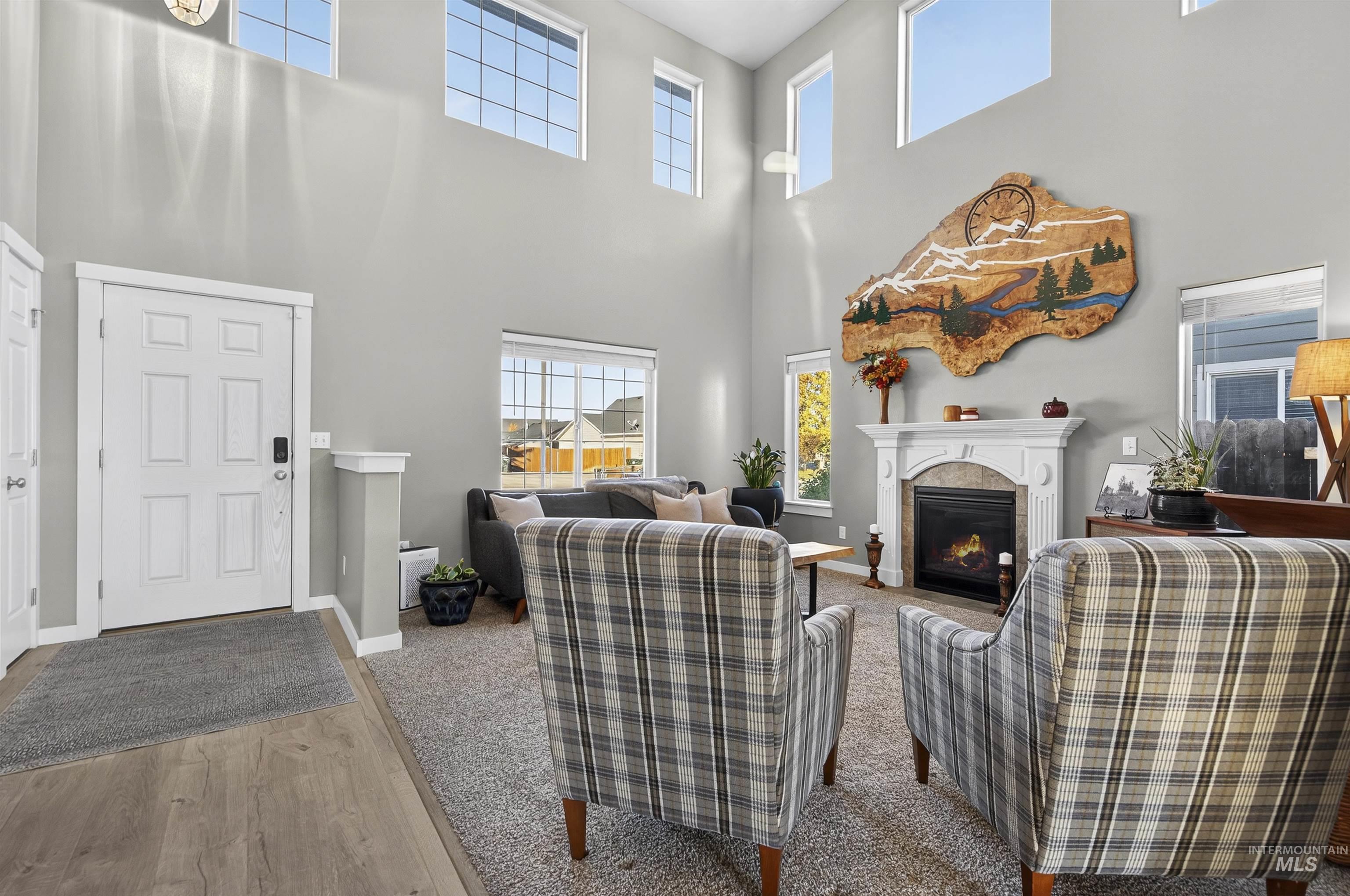 Living area featuring a fireplace with flush hearth, a high ceiling, healthy amount of natural light, wood finished floors, and carpet flooring