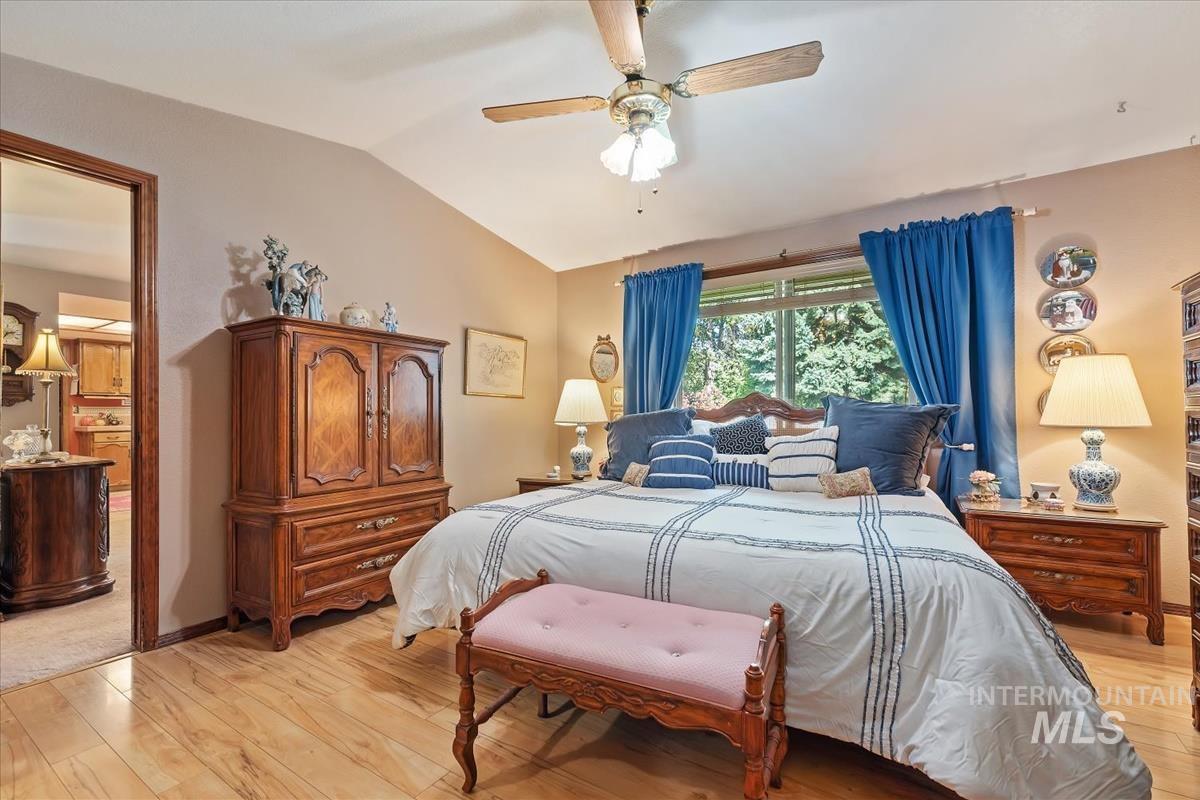 Bedroom with light wood finished floors, lofted ceiling, and a ceiling fan