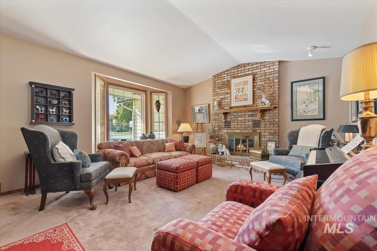 Carpeted living room featuring lofted ceiling and a brick fireplace