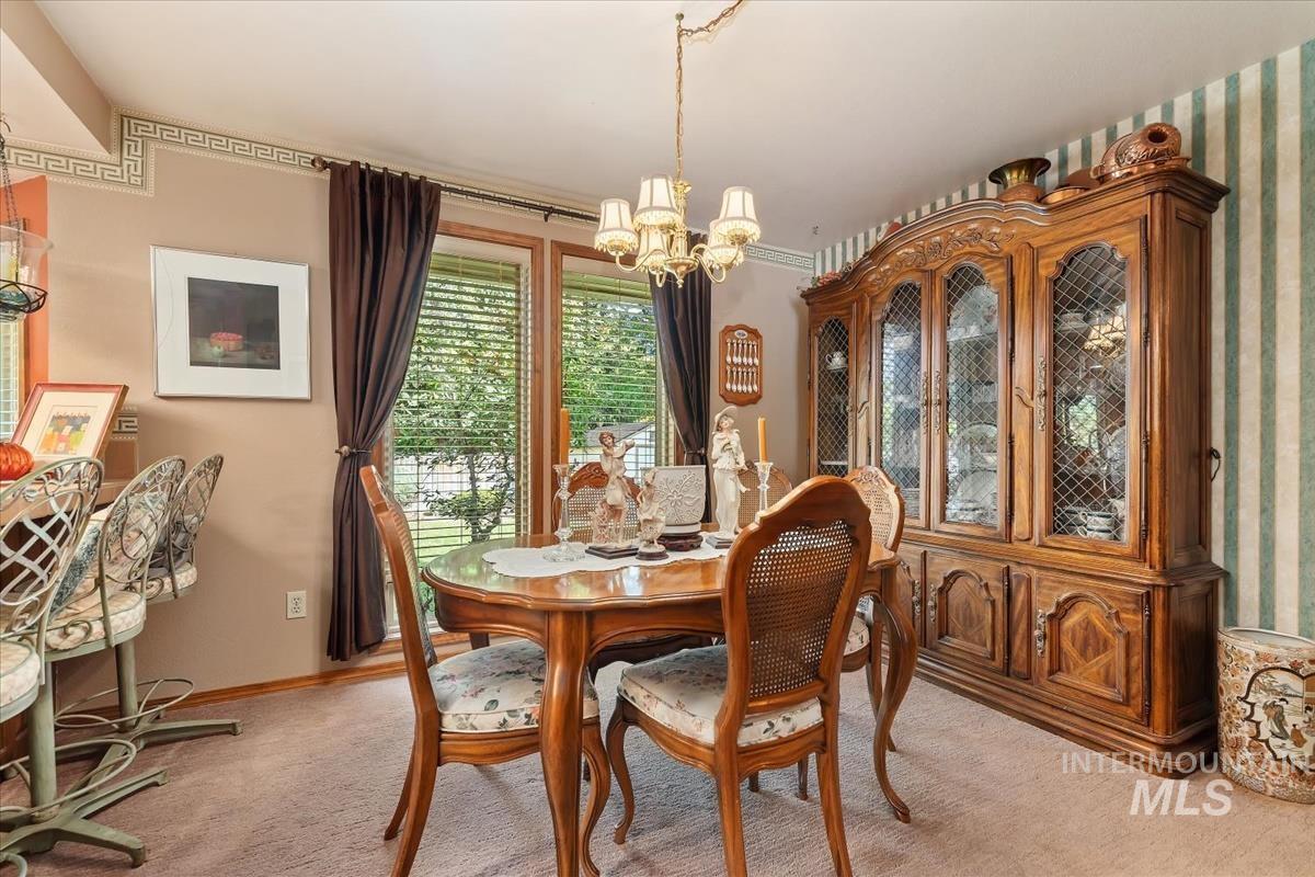 Carpeted dining area with a chandelier and baseboards