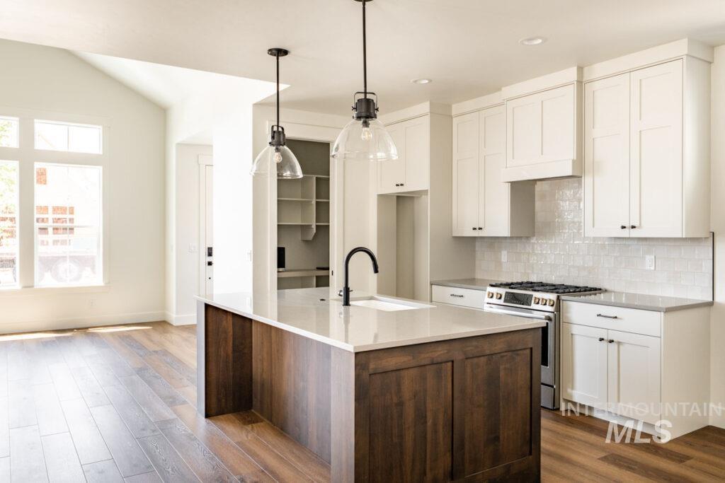 Kitchen featuring stainless steel range with gas cooktop, white cabinets, dark wood-type flooring, backsplash, and recessed lighting
