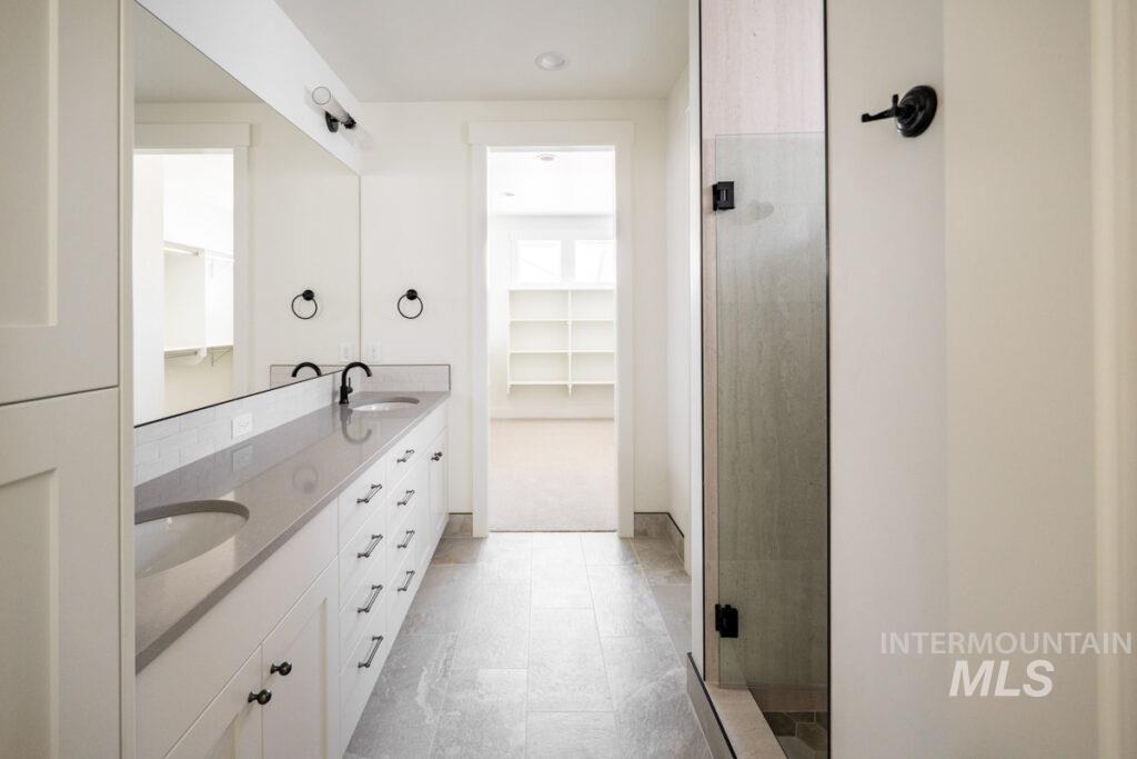 Bathroom featuring double vanity, a shower stall, and a spacious closet