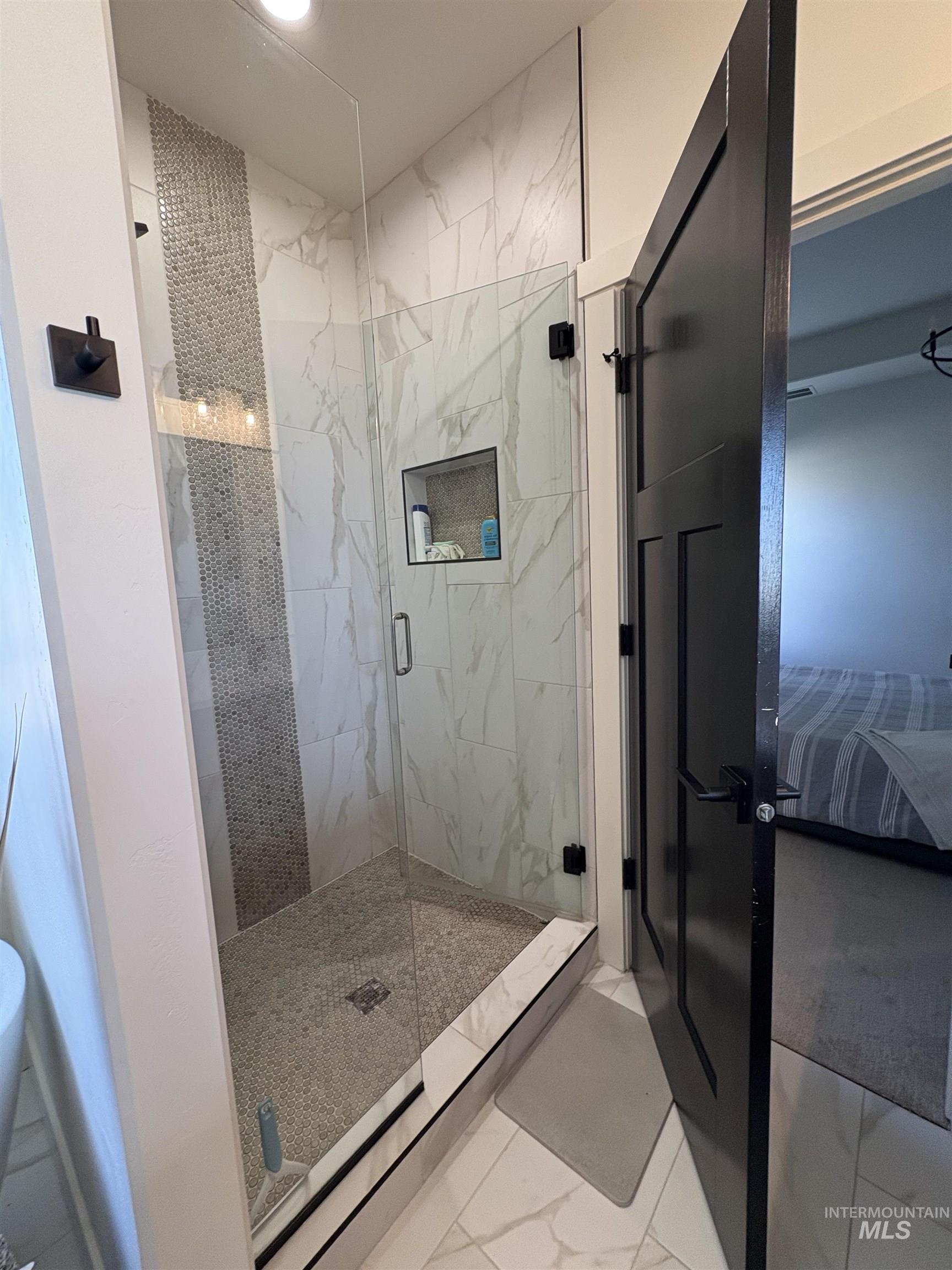 Ensuite bathroom featuring a marble finish shower and marble finish flooring