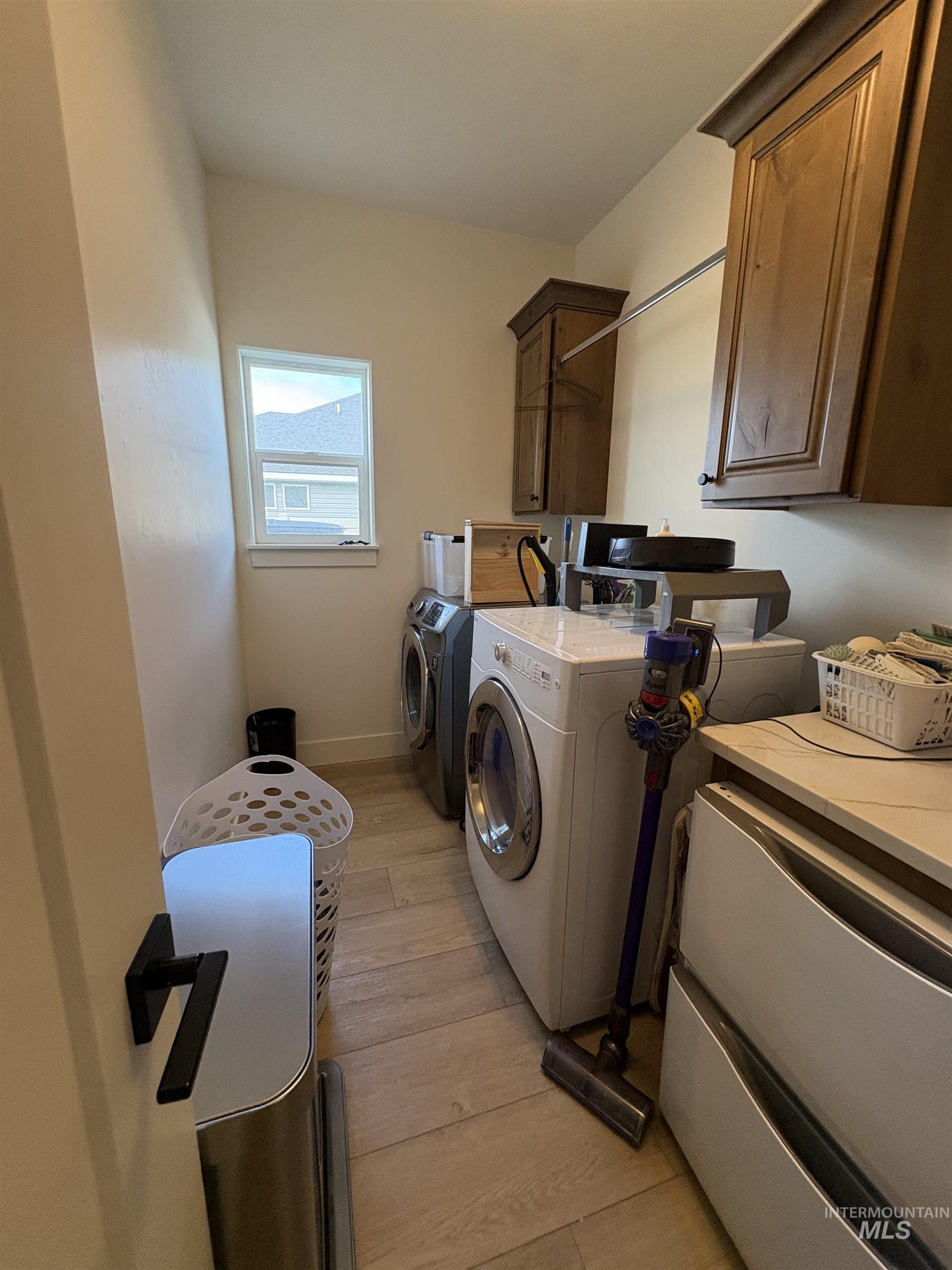 Laundry area featuring light wood-style floors, cabinet space, and separate washer and dryer