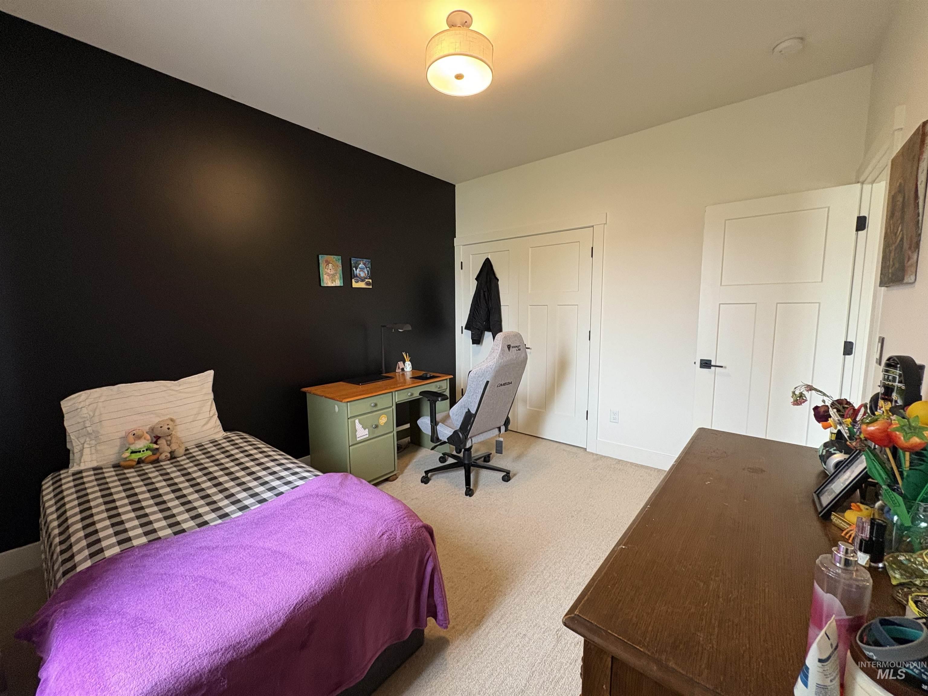 Carpeted bedroom featuring an office area and a closet