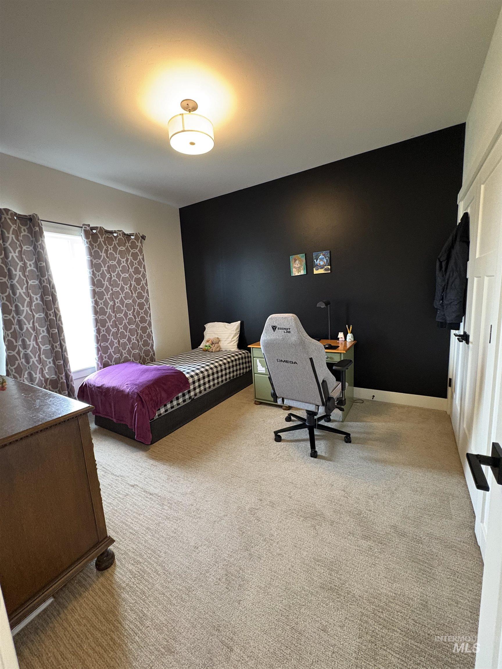 Bedroom with light colored carpet and an office area