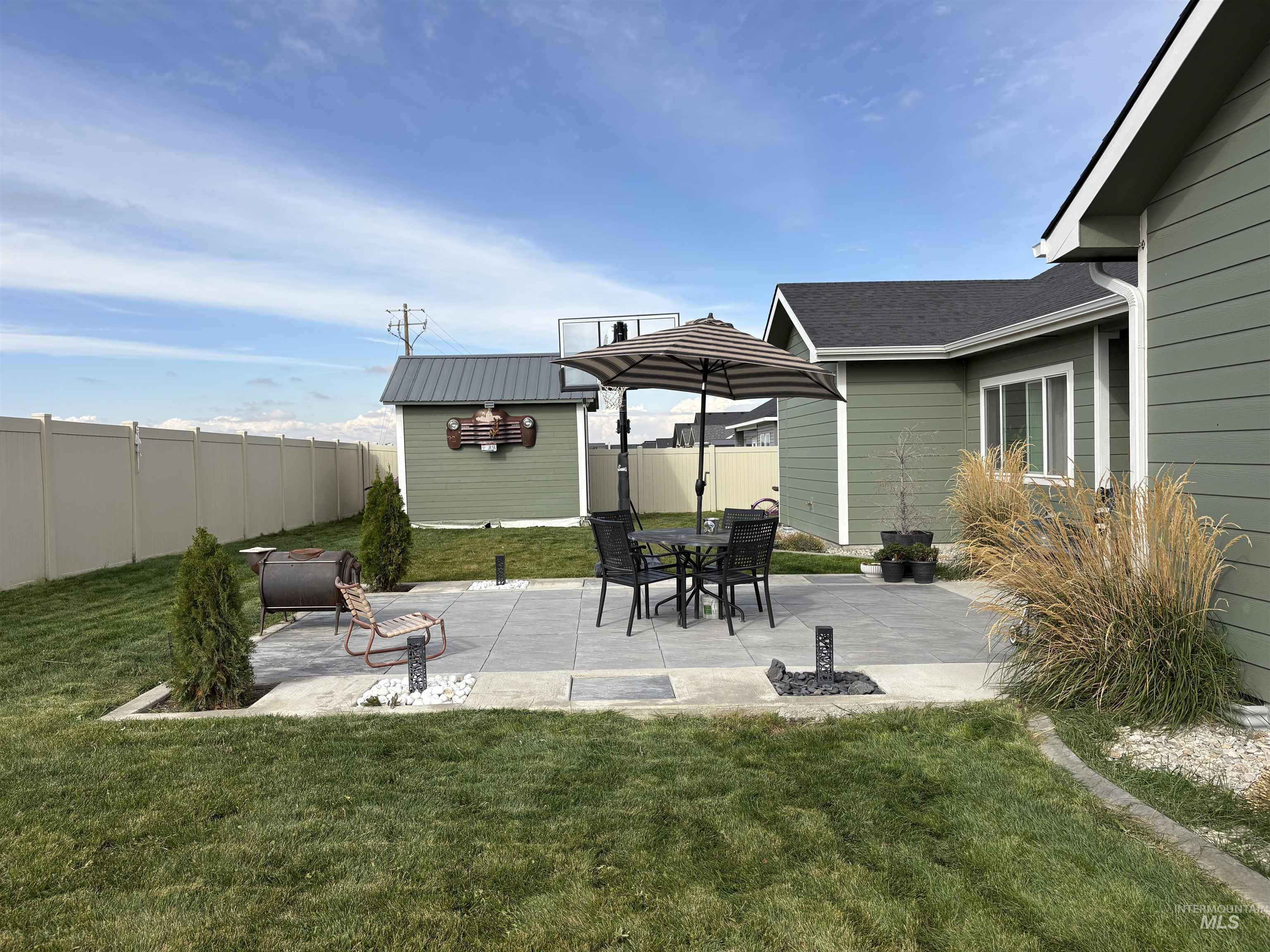 Fenced backyard with an outbuilding and a patio area