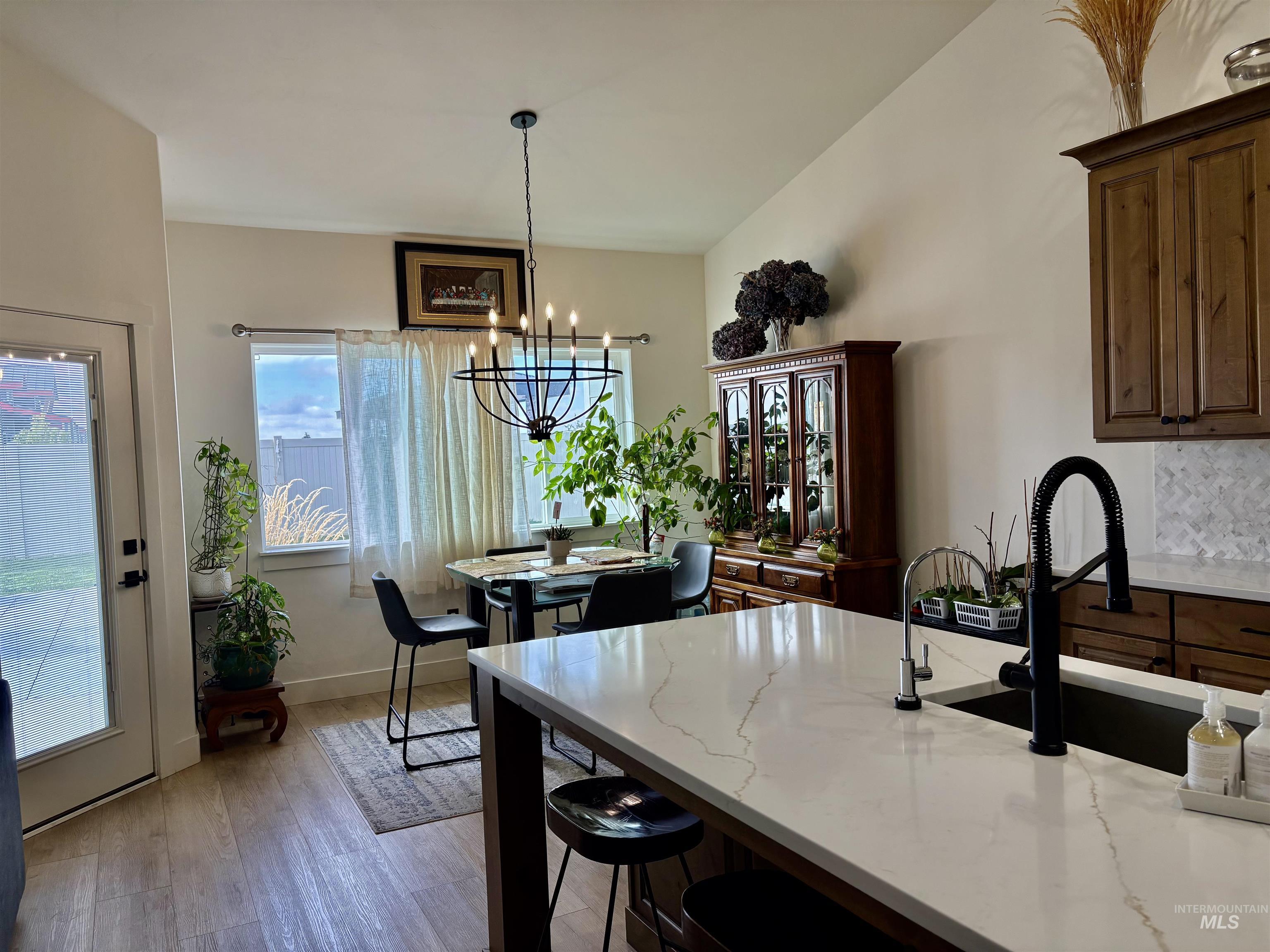 Kitchen featuring healthy amount of natural light, light stone countertops, light wood-style floors, and decorative light fixtures
