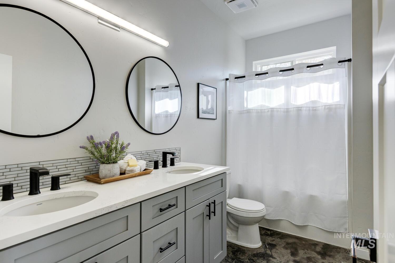 Full bath with tasteful backsplash, double vanity, and shower / tub combo