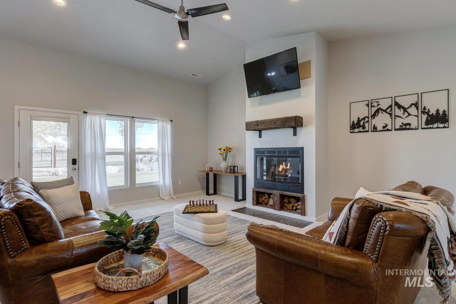 Living area featuring a glass covered fireplace, recessed lighting, carpet flooring, ceiling fan, and high vaulted ceiling