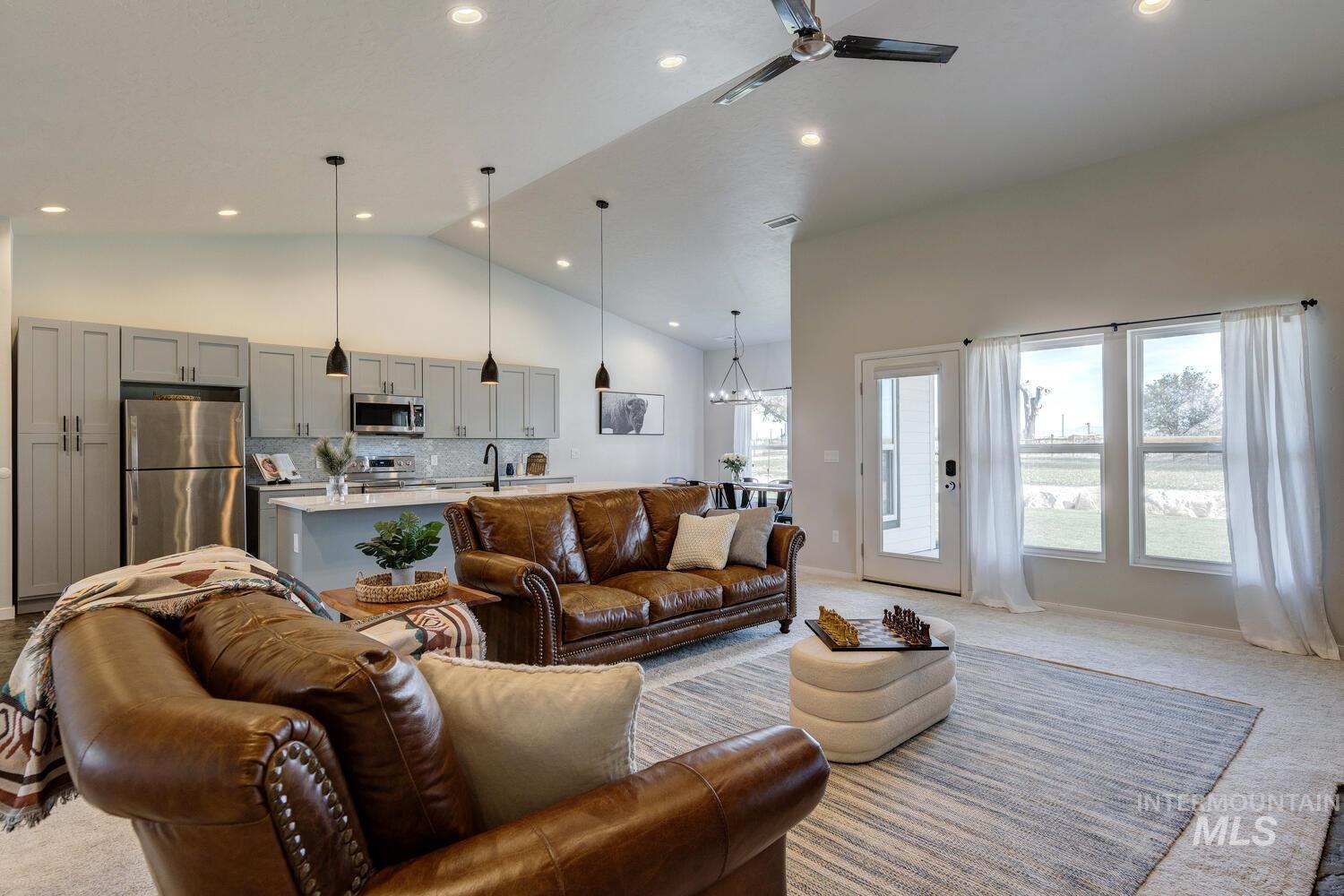Carpeted living room with high vaulted ceiling, a chandelier, ceiling fan, and recessed lighting