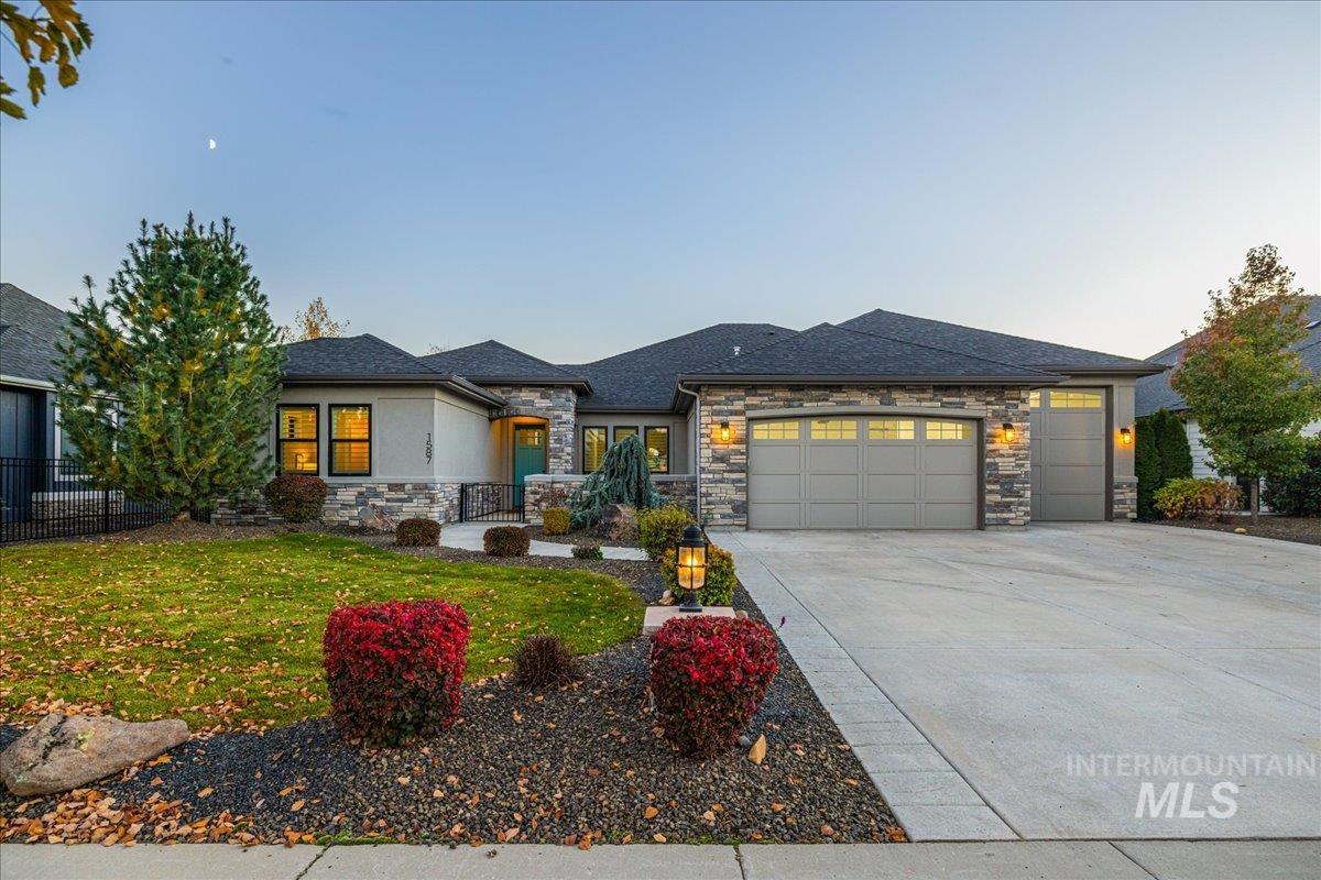 Prairie-style house with stone siding, an attached garage, concrete driveway, and a shingled roof