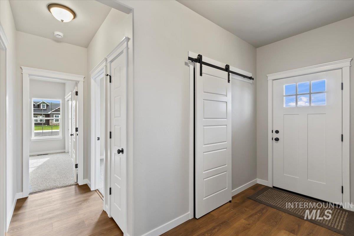 Entrance foyer with a barn door, healthy amount of natural light, and dark wood-style floors