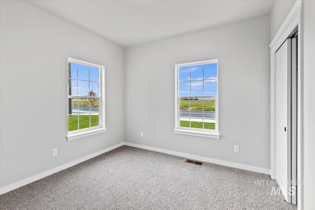 Unfurnished bedroom with light carpet, multiple windows, and a closet