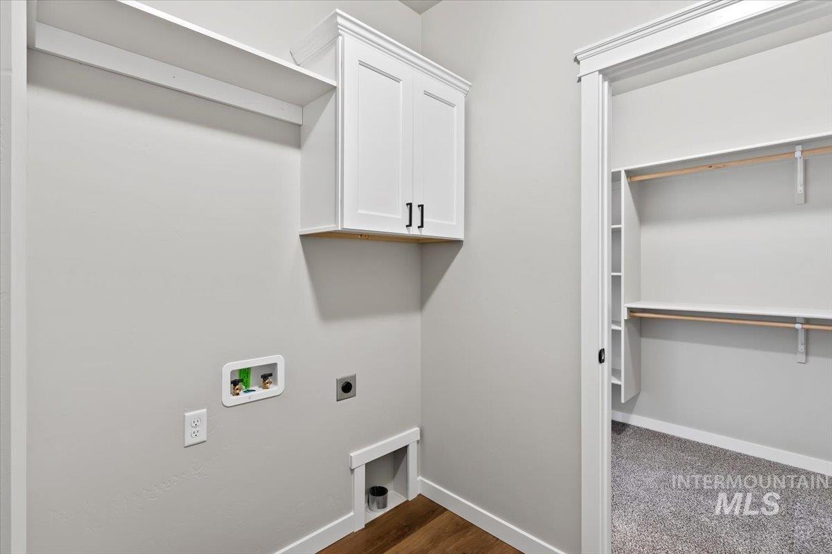 Washroom featuring hookup for an electric dryer, cabinet space, washer hookup, and dark wood-style flooring