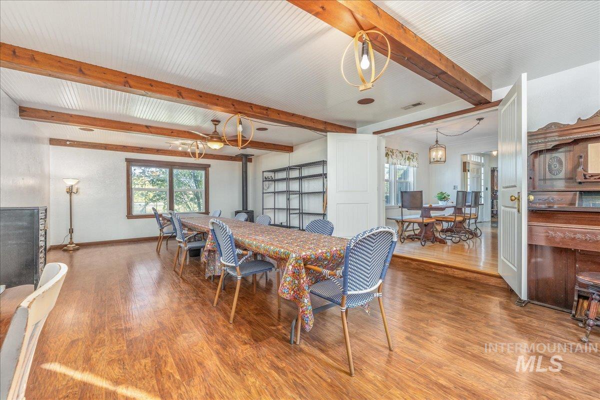 Dining space with wood finished floors, beam ceiling, and a chandelier