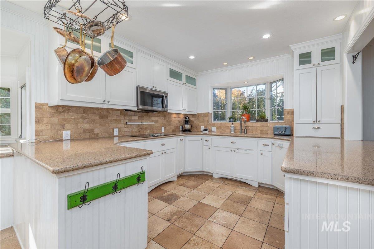 Kitchen featuring glass insert cabinets, white cabinets, a peninsula, crown molding, and recessed lighting