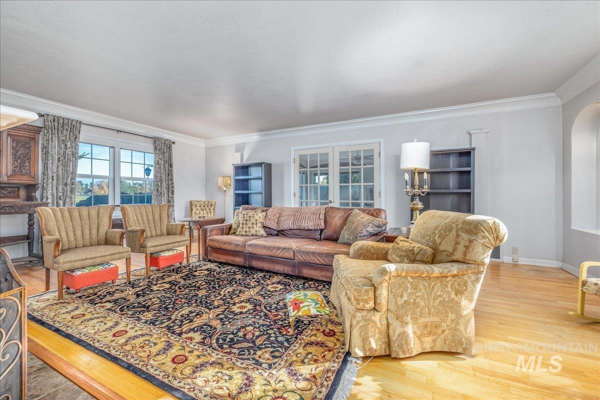Living room with light wood finished floors, ornamental molding, and arched walkways