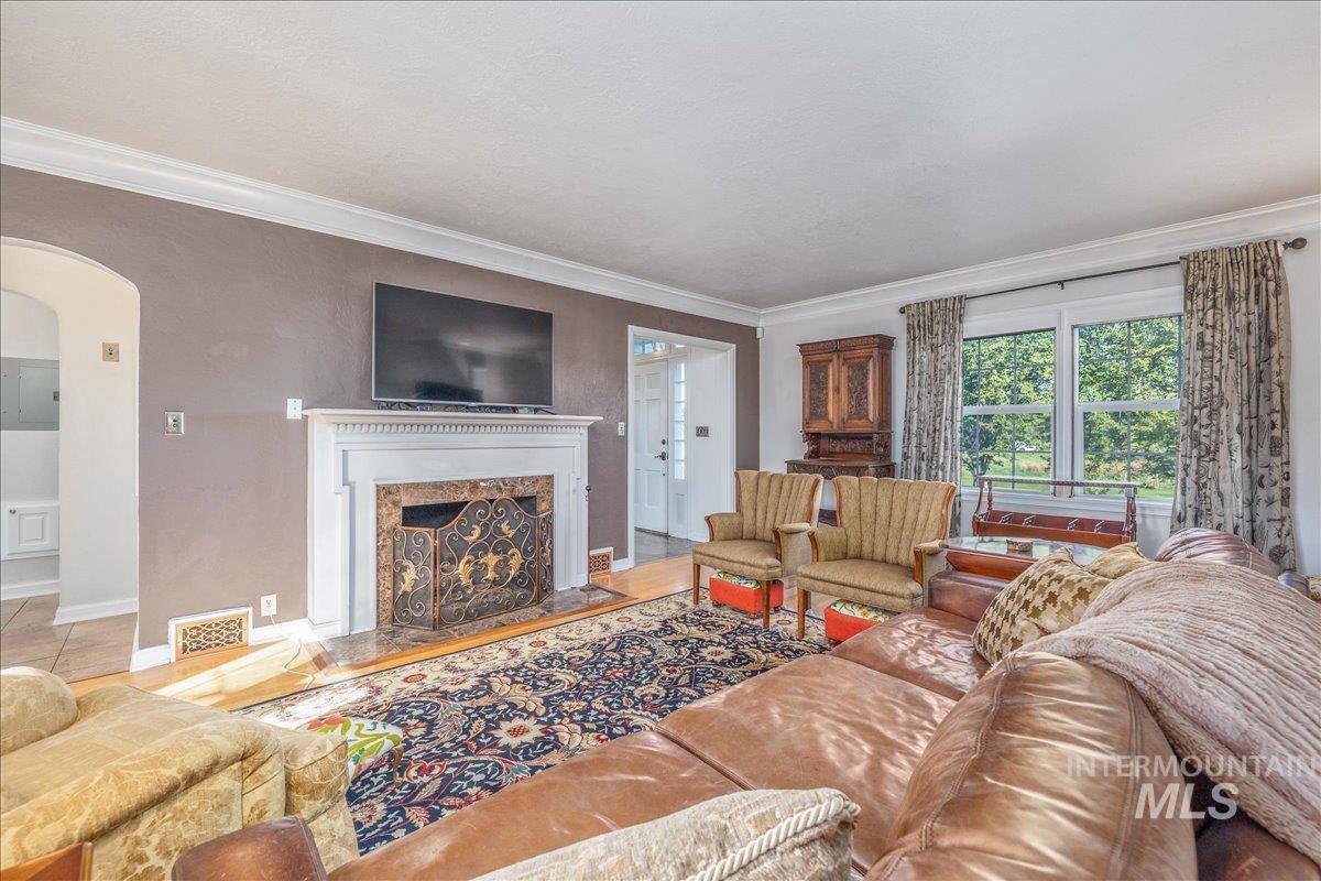Living area featuring ornamental molding, arched walkways, and a high end fireplace