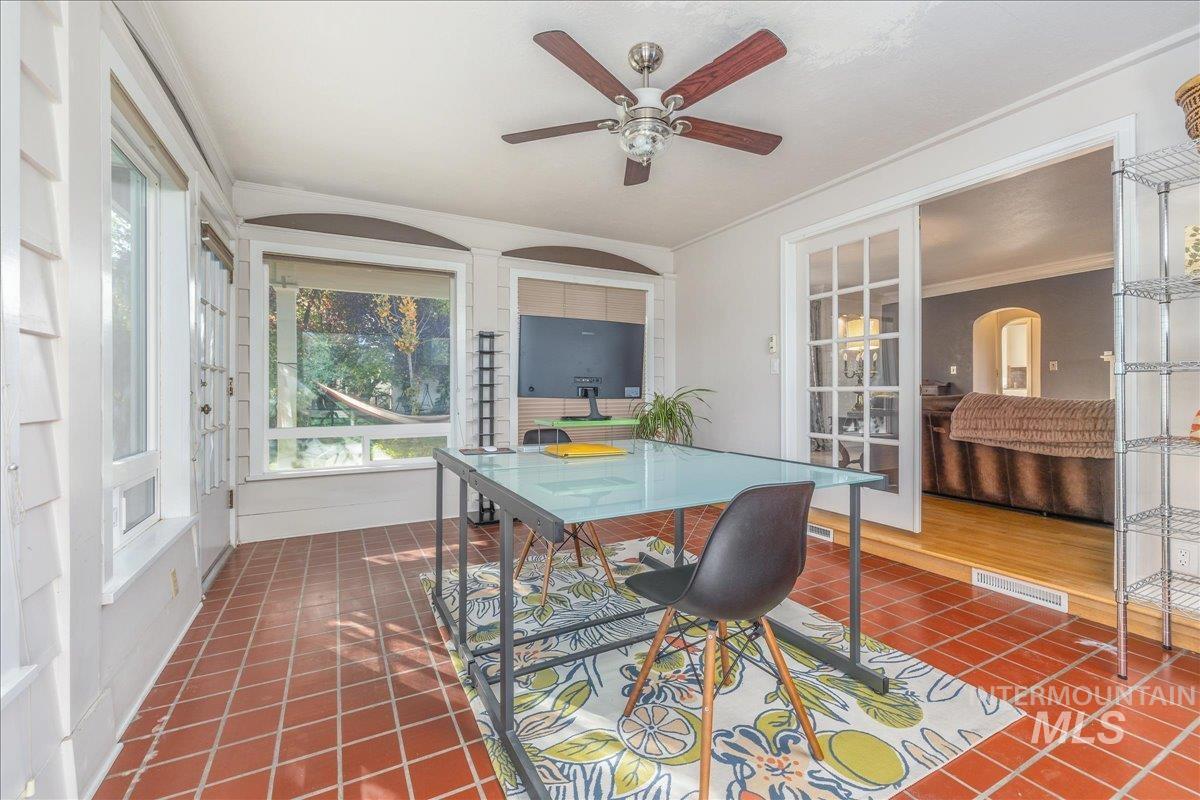 Dining room with dark tile patterned flooring, crown molding, and a ceiling fan