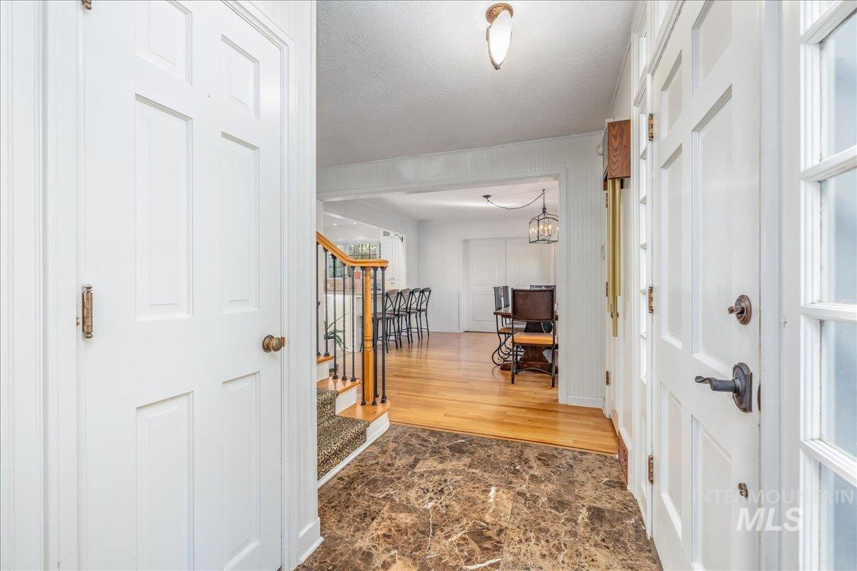 Entrance foyer with stone finish flooring, stairs, a textured ceiling, and a chandelier