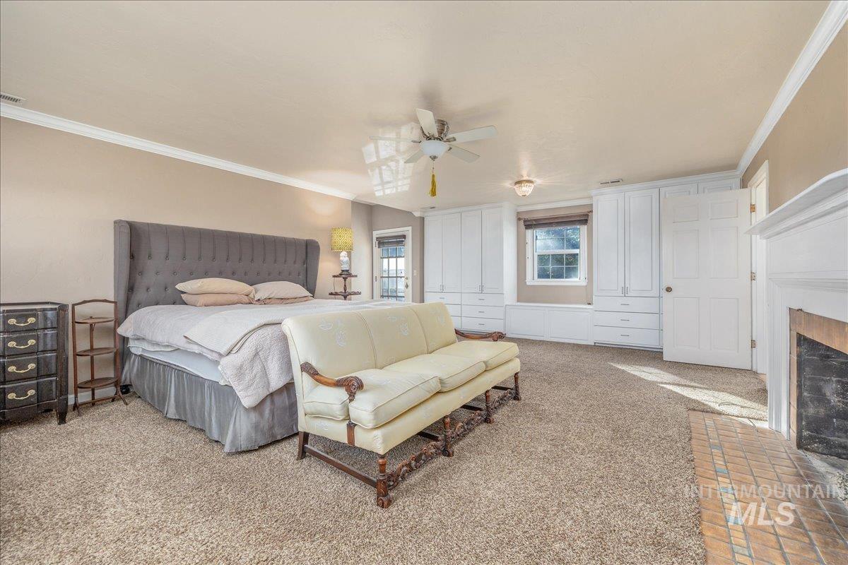 Carpeted bedroom featuring ornamental molding, a closet, ceiling fan, and a brick fireplace