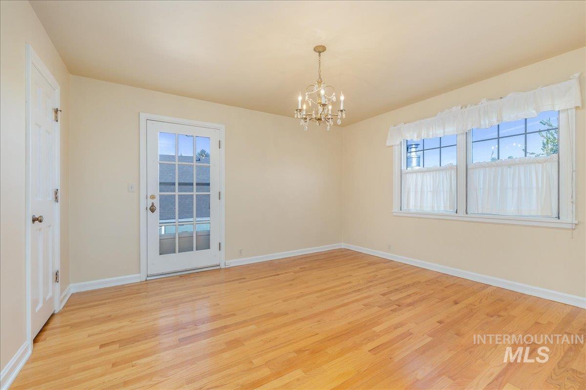 Unfurnished room featuring plenty of natural light, light wood-style floors, and a chandelier