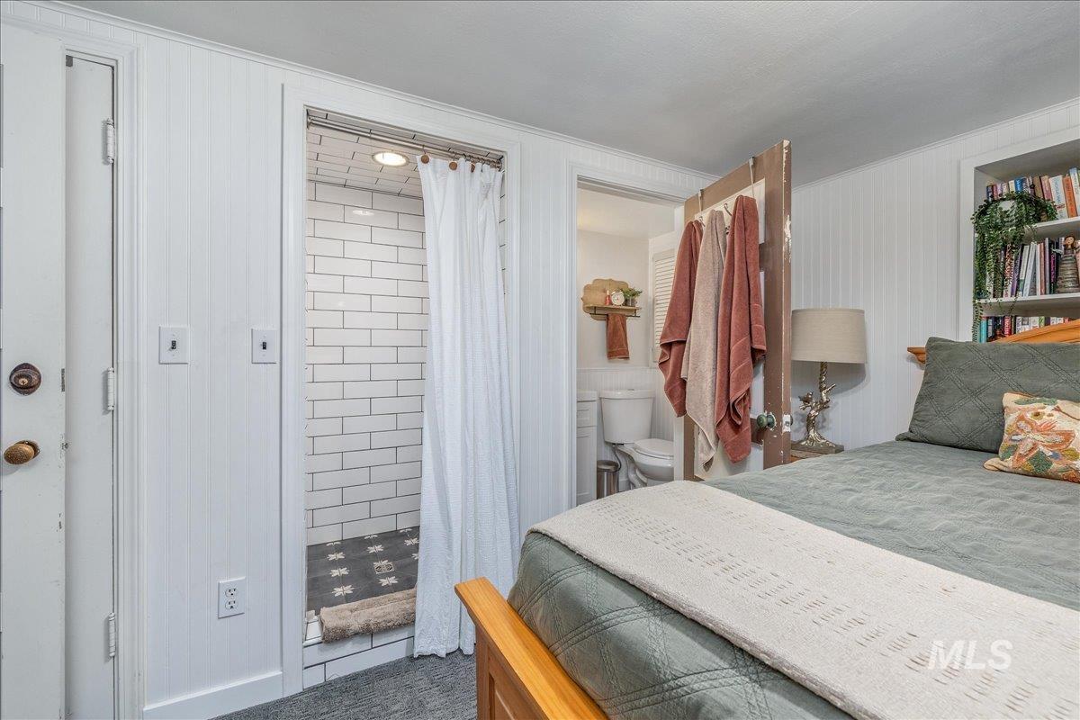 Tiled bedroom featuring crown molding and ensuite bathroom
