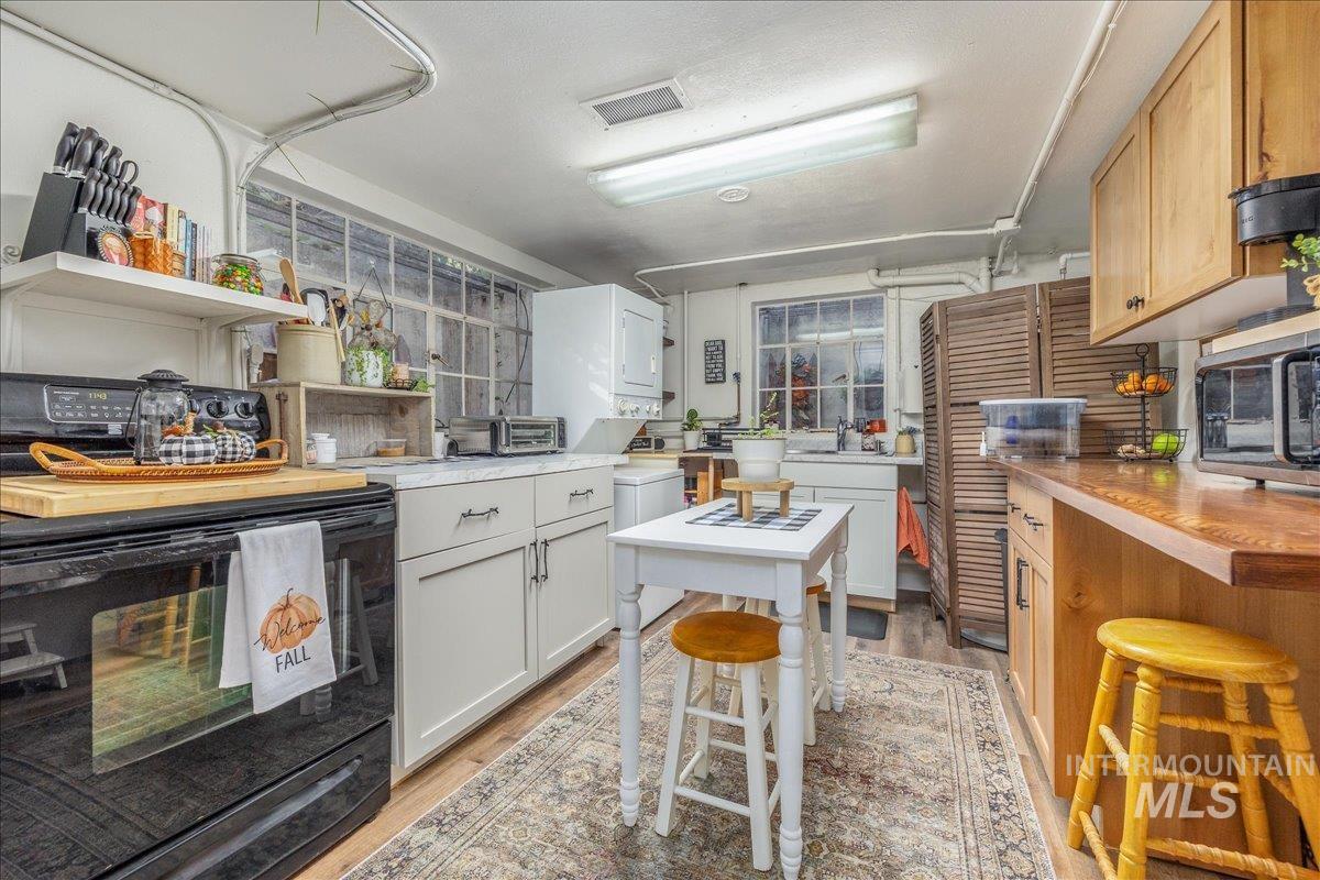 Kitchen featuring black electric range oven, light wood-type flooring, and open shelves