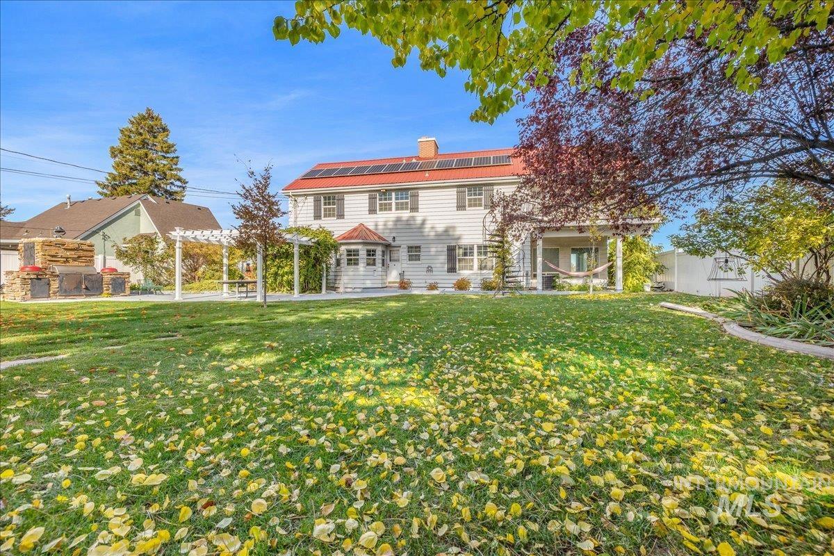Rear view of house featuring a chimney and solar panels