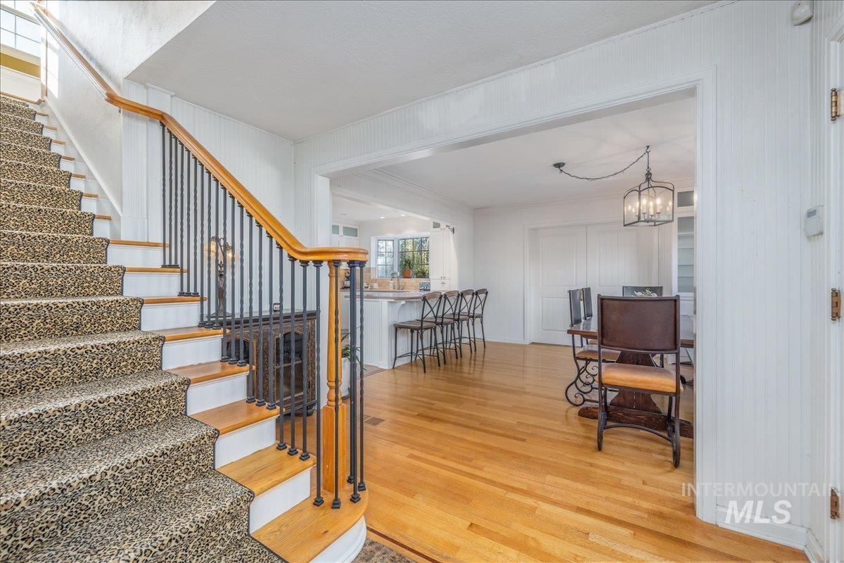 Stairs featuring wood finished floors, crown molding, and a chandelier